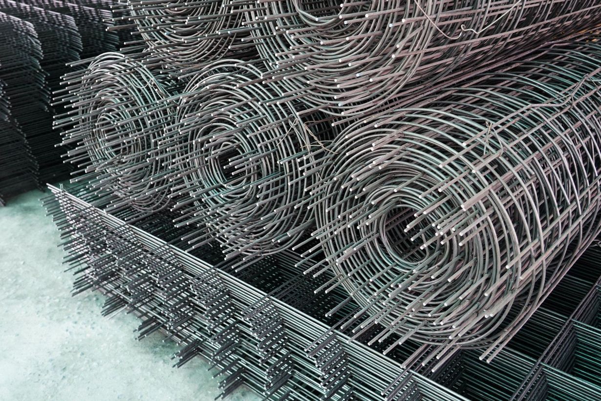 Stacks of coiled metal wire mesh rolls in a storage area