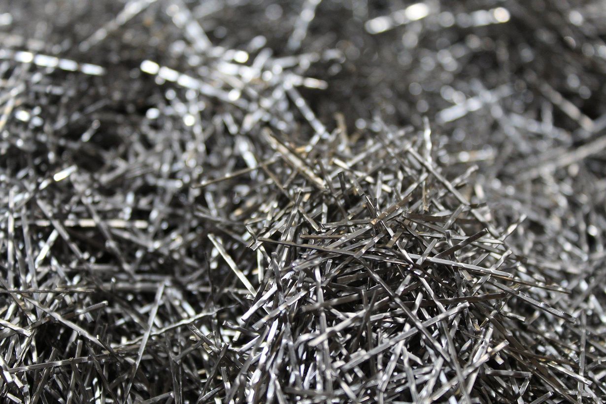 Close-up of tangled silver metal shavings or wire scraps on a dark surface