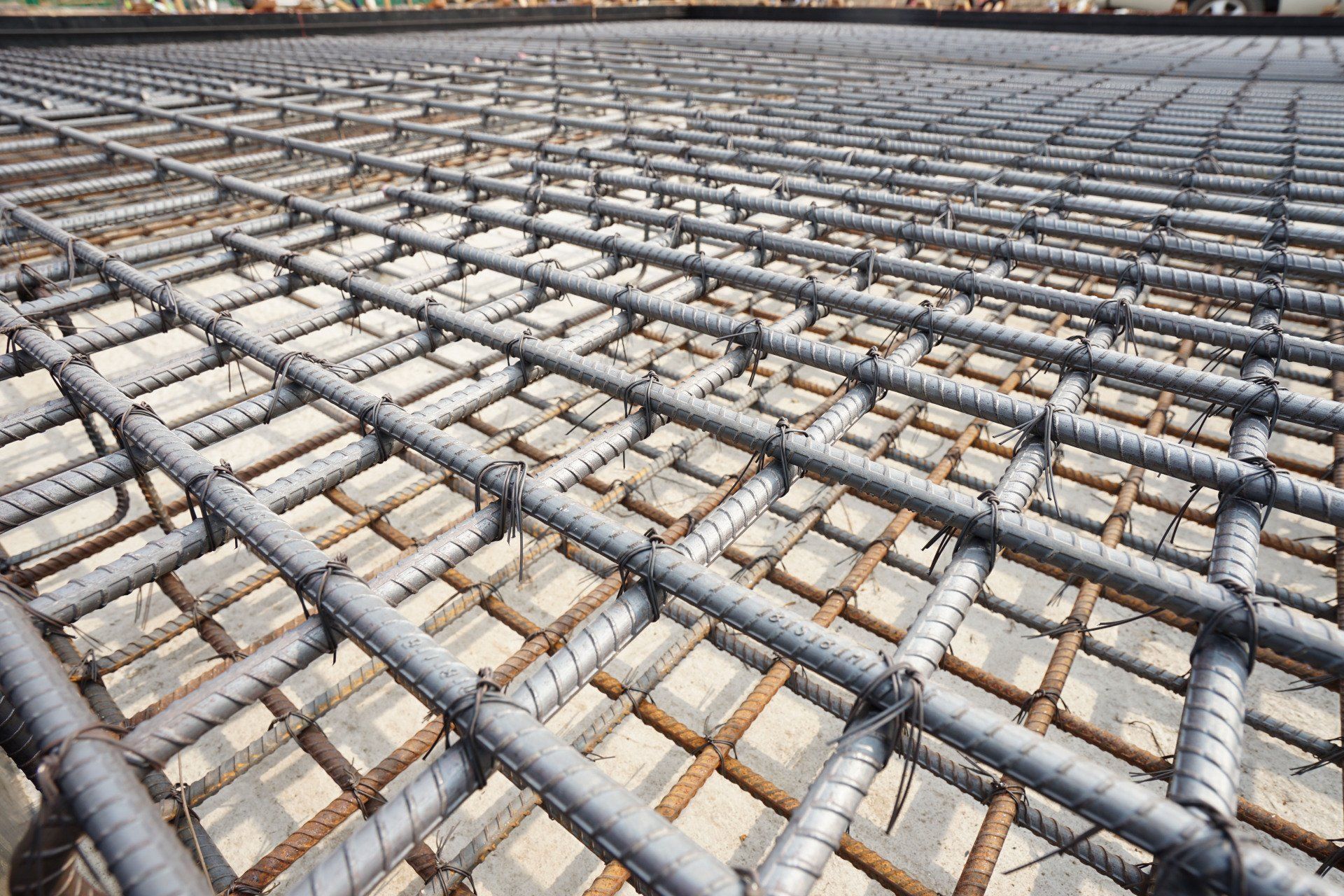 Steel rebar grid laid over a concrete foundation under construction