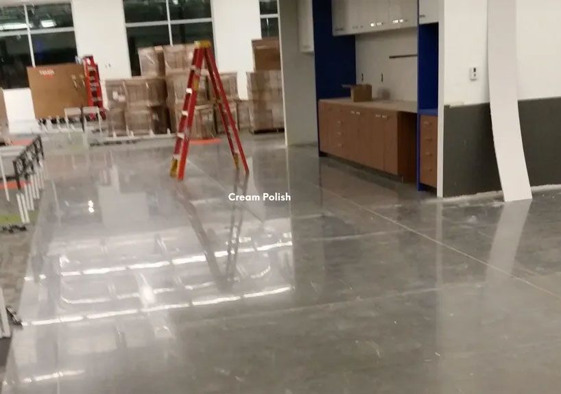 Polished concrete floor in a construction site, with ladders, boxes, and cabinets visible.