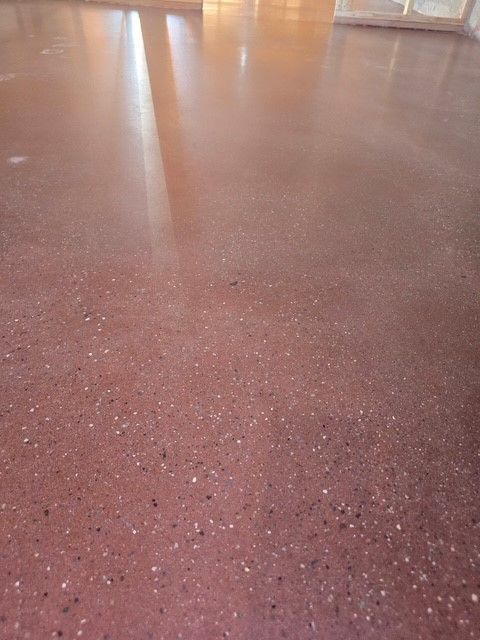 Red polished concrete floor with flecks, reflecting light.