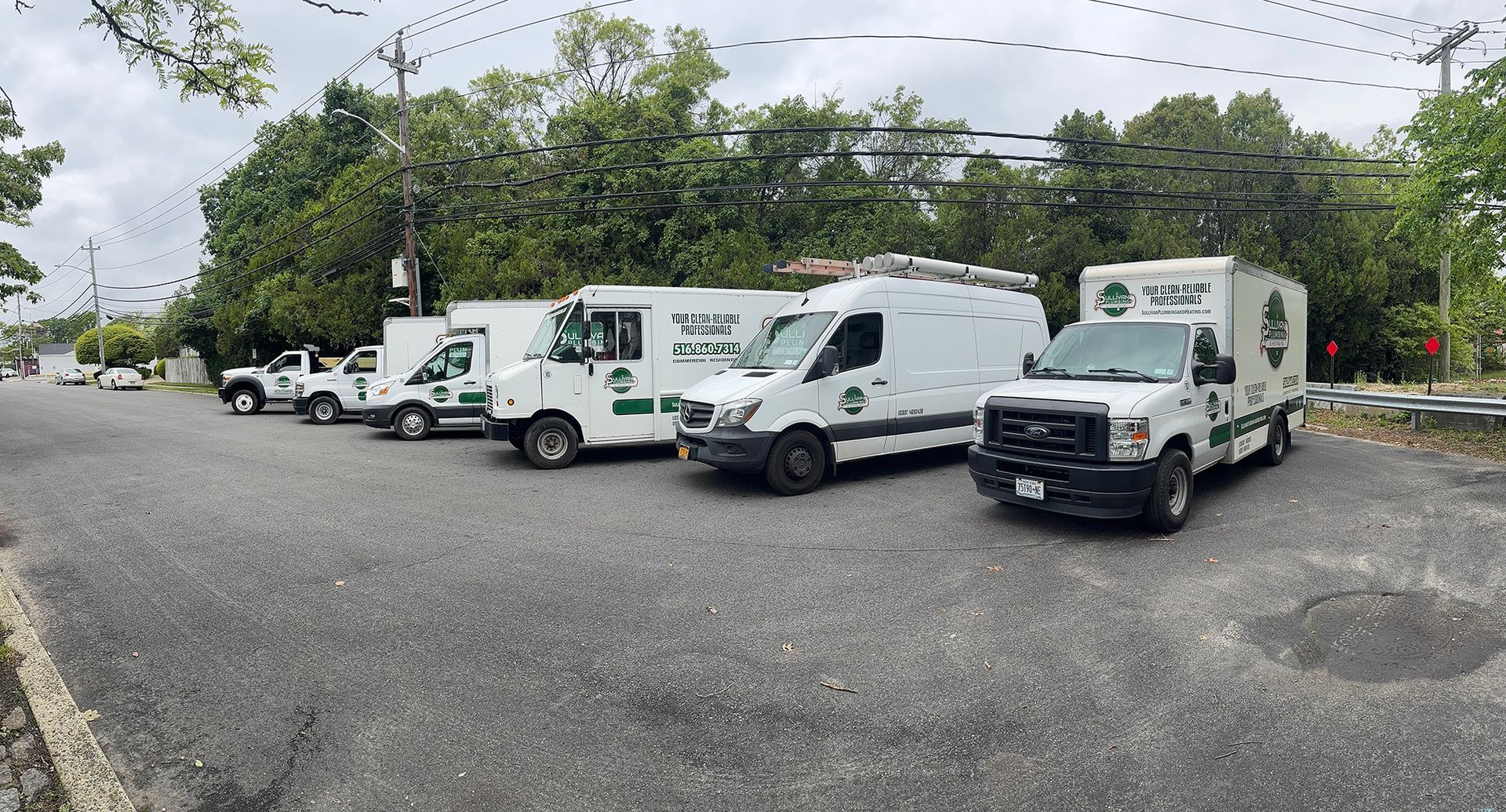 A row of white vans are parked in a parking lot.