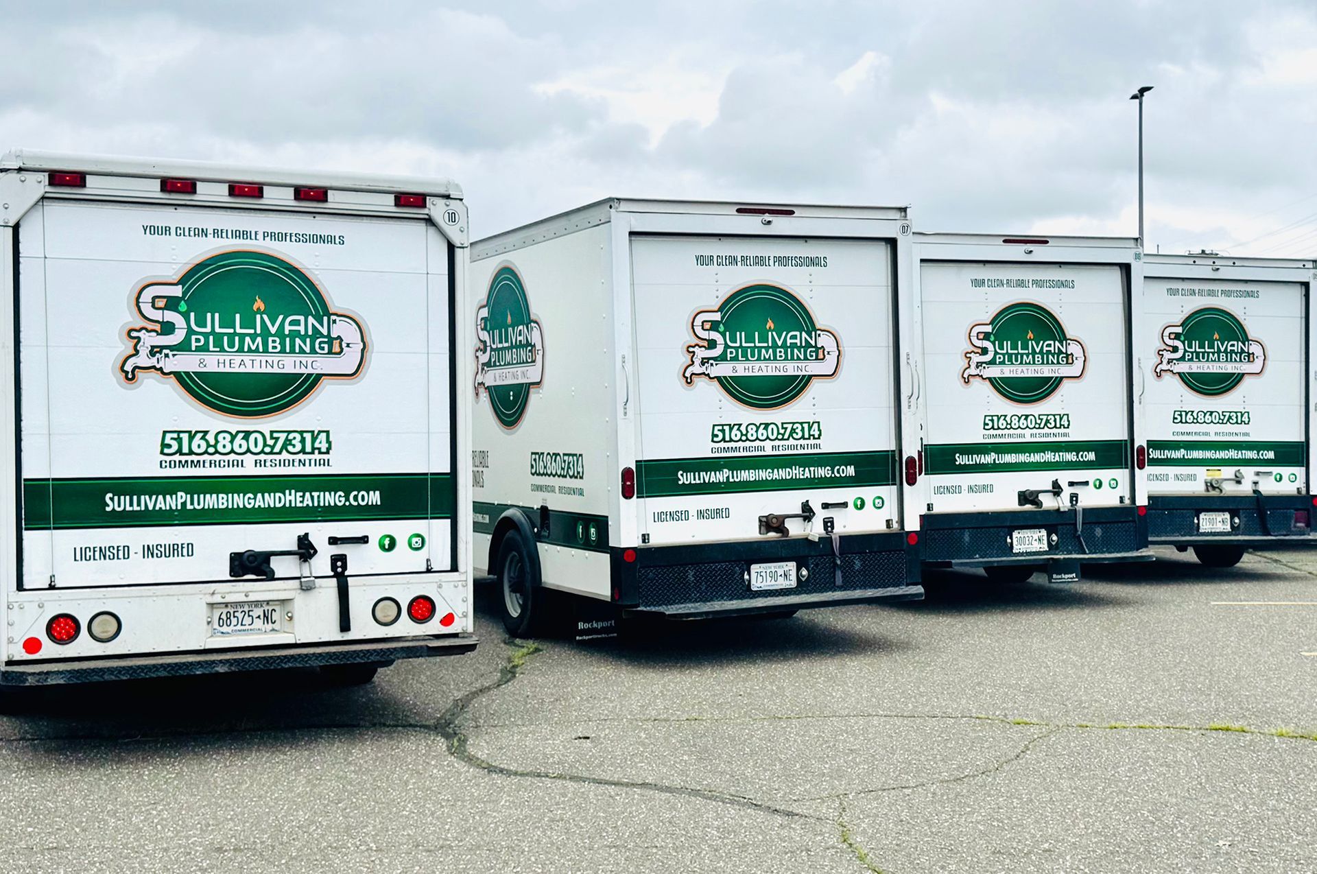 A row of trucks are parked in a parking lot.