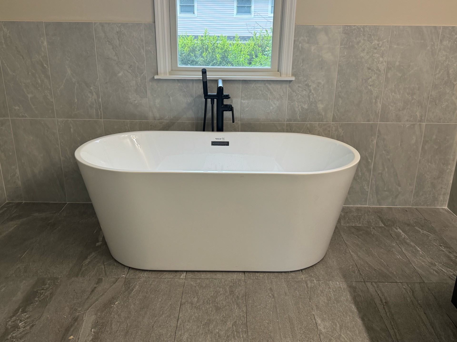 A white bathtub is sitting in a bathroom next to a window.