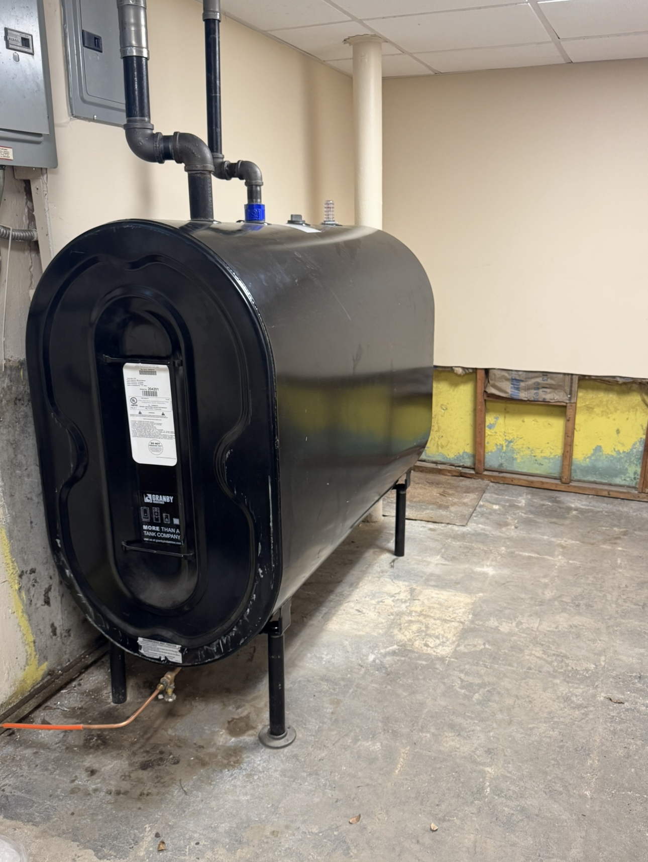 A large black tank is sitting in a room next to a wall.