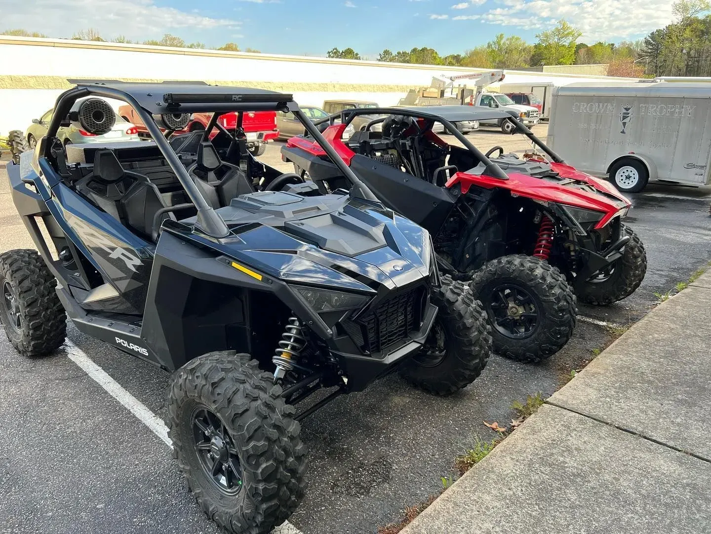 Two side-by-side ATVs, one black and one red, parked outdoors.