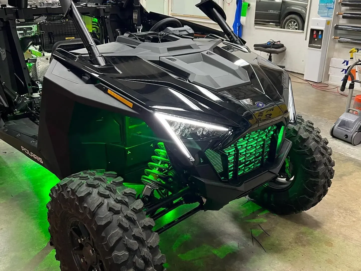 Black and green off-road vehicle with glowing green undercarriage and headlights.