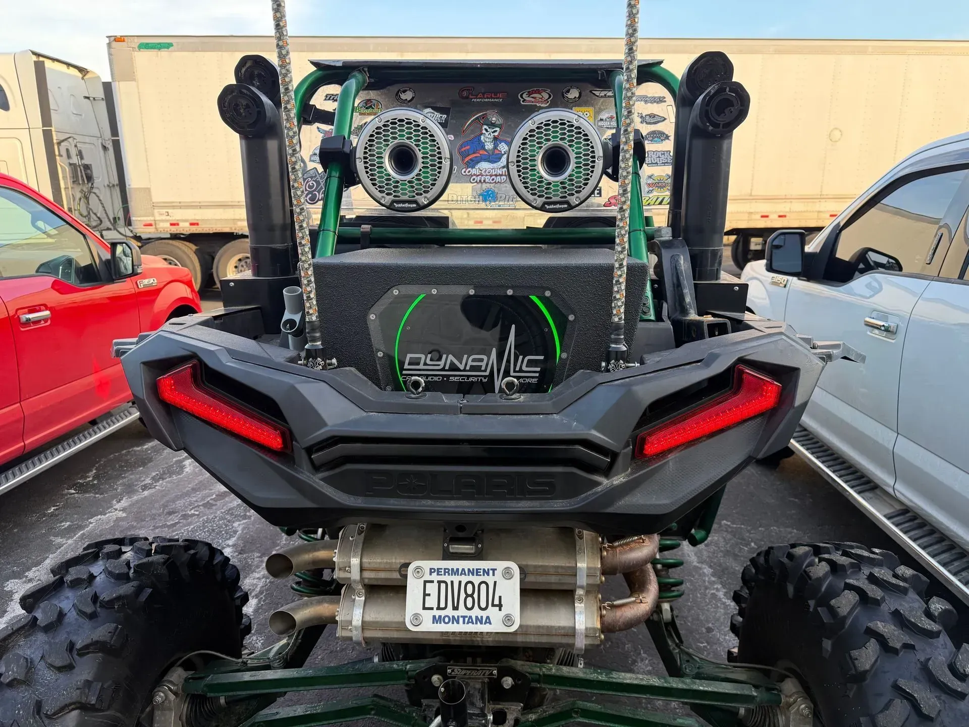 Rear view of a green and black ATV with a custom sound system and exhaust.