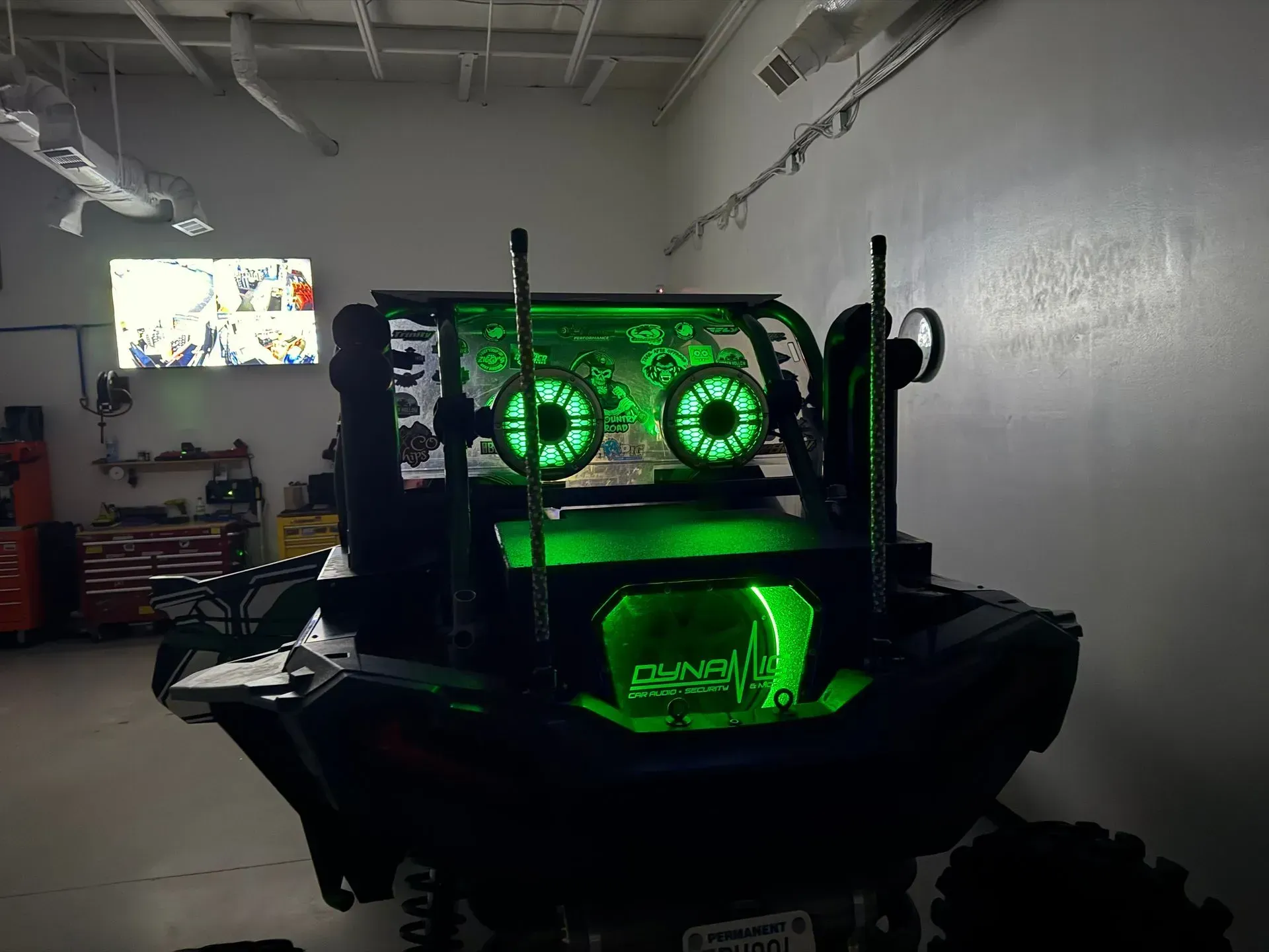 An off-road vehicle with bright green LED lights illuminating its structure in a garage.