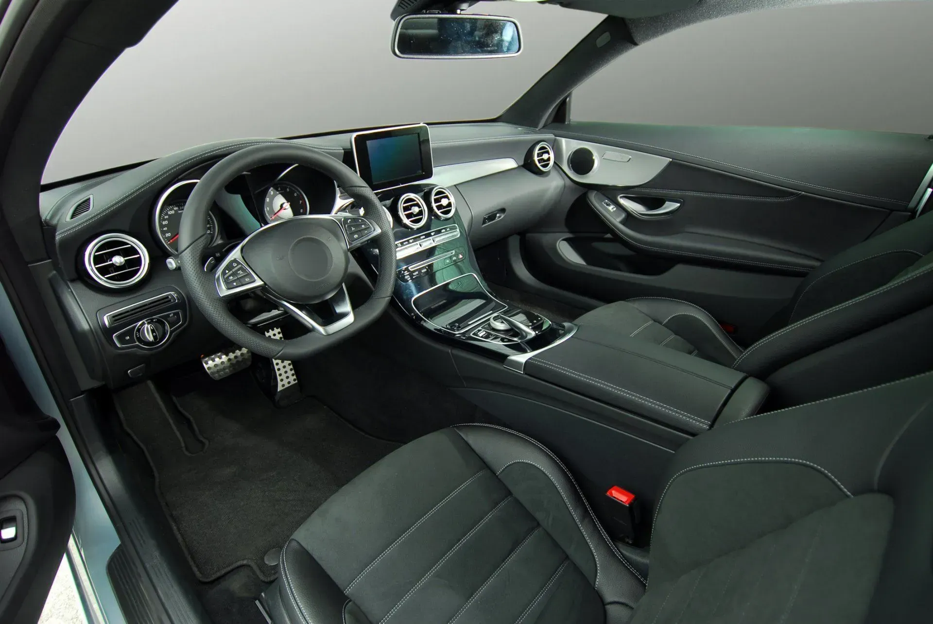 Interior of a modern car, black leather seats, dashboard, and steering wheel.