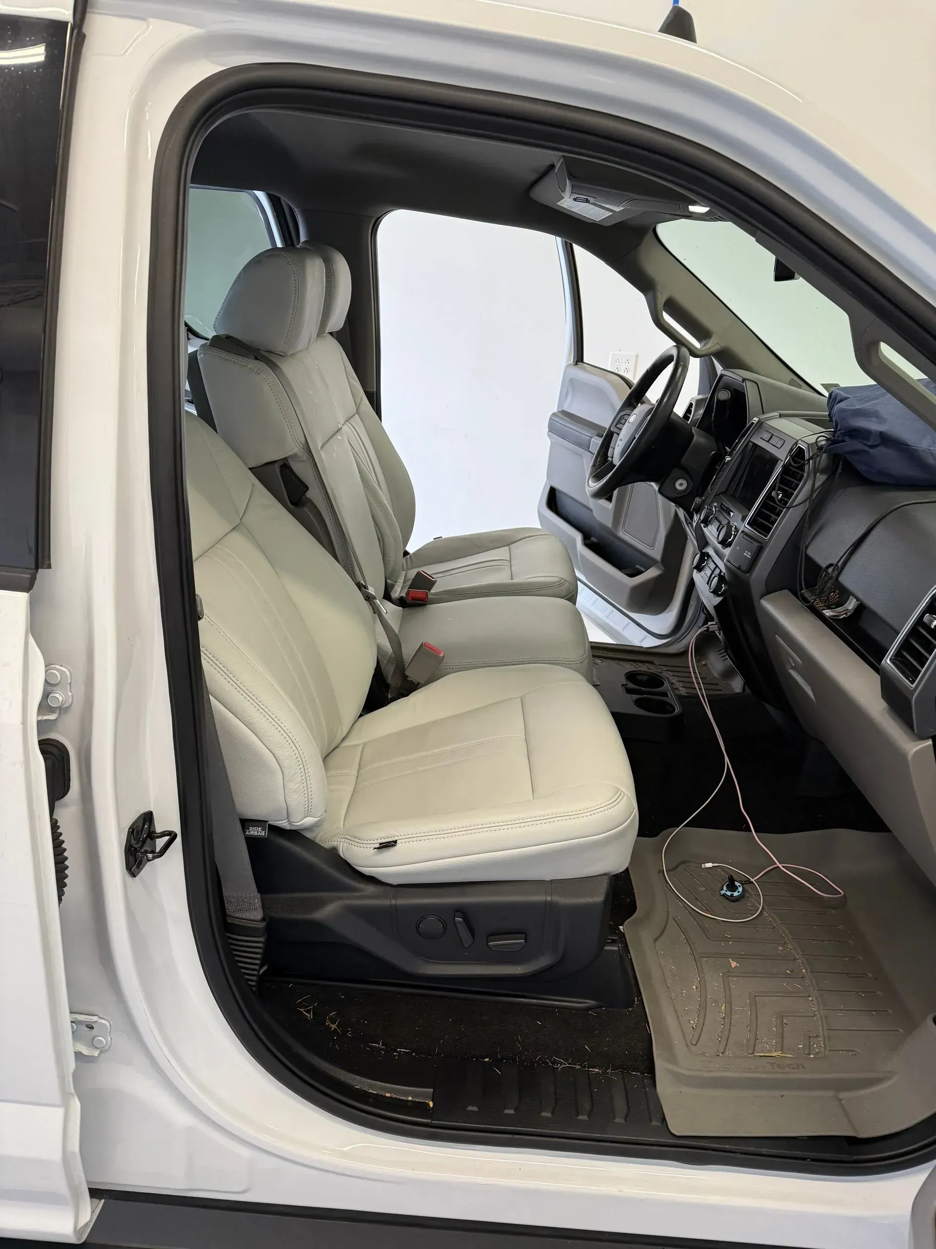 White interior of a truck, front seats visible, steering wheel, and floor mat.