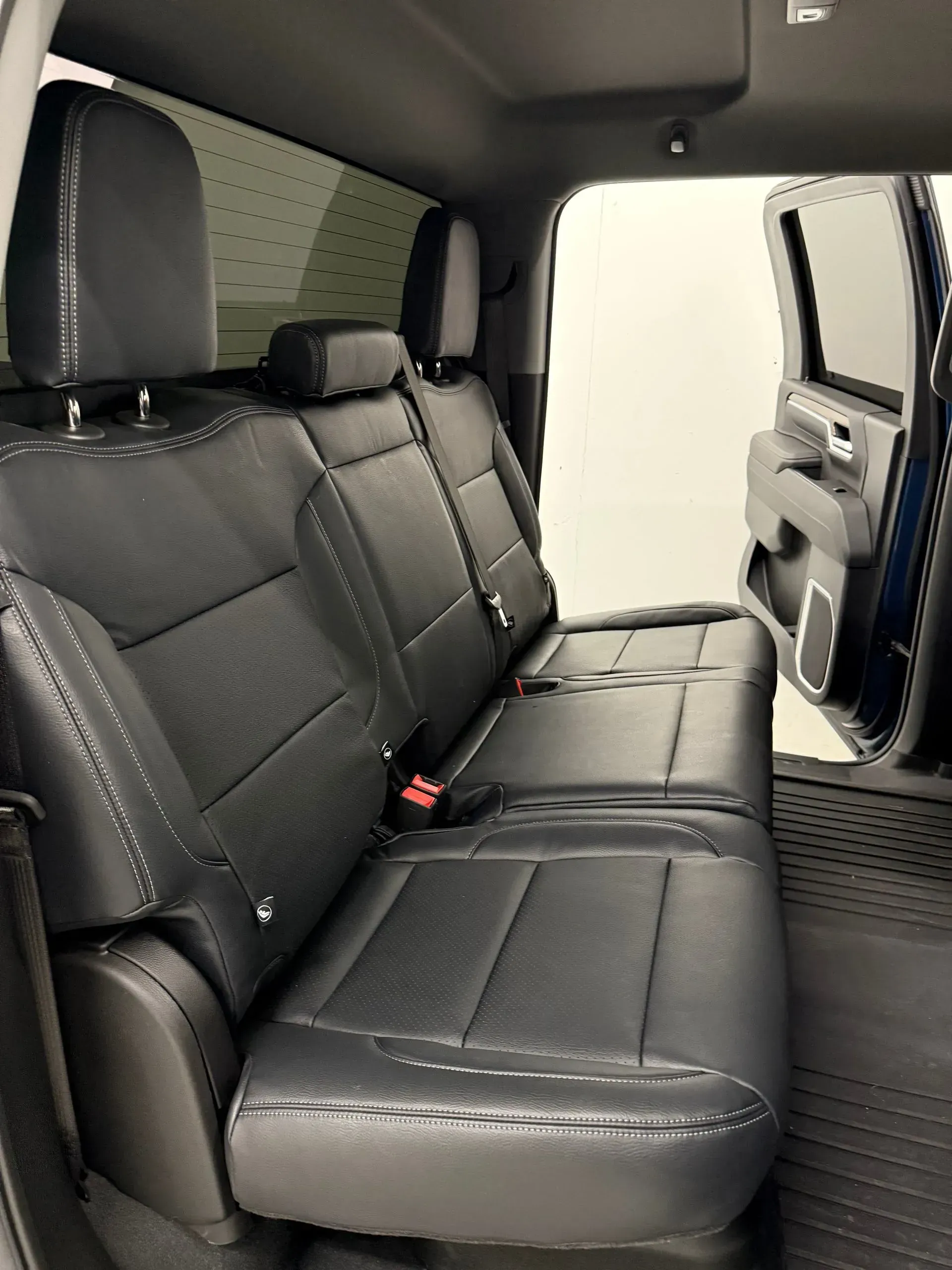 Black leather truck backseat with headrests, open door visible.