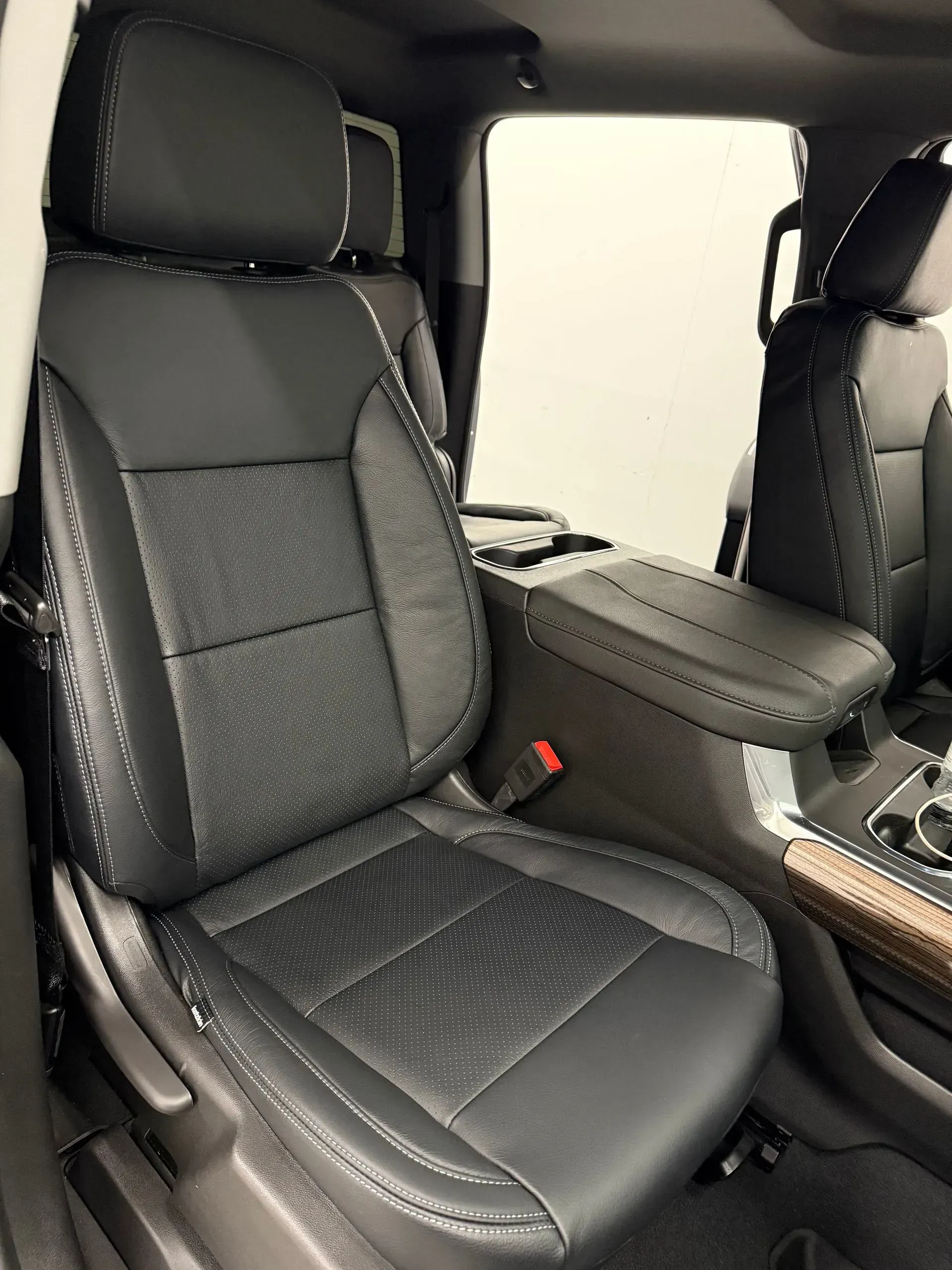 Black leather car seat with perforated bottom, headrest, and armrest visible.