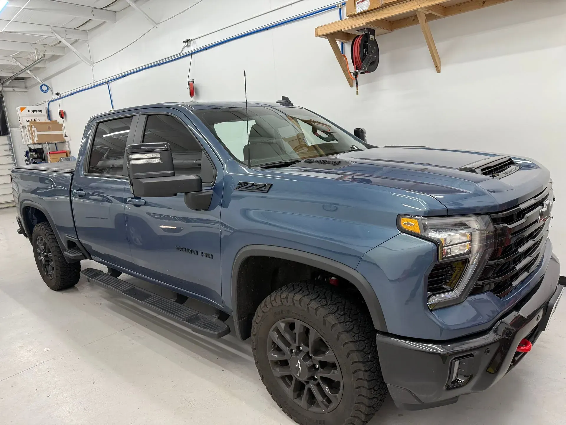 Blue Chevrolet truck, black rims, parked inside a garage.