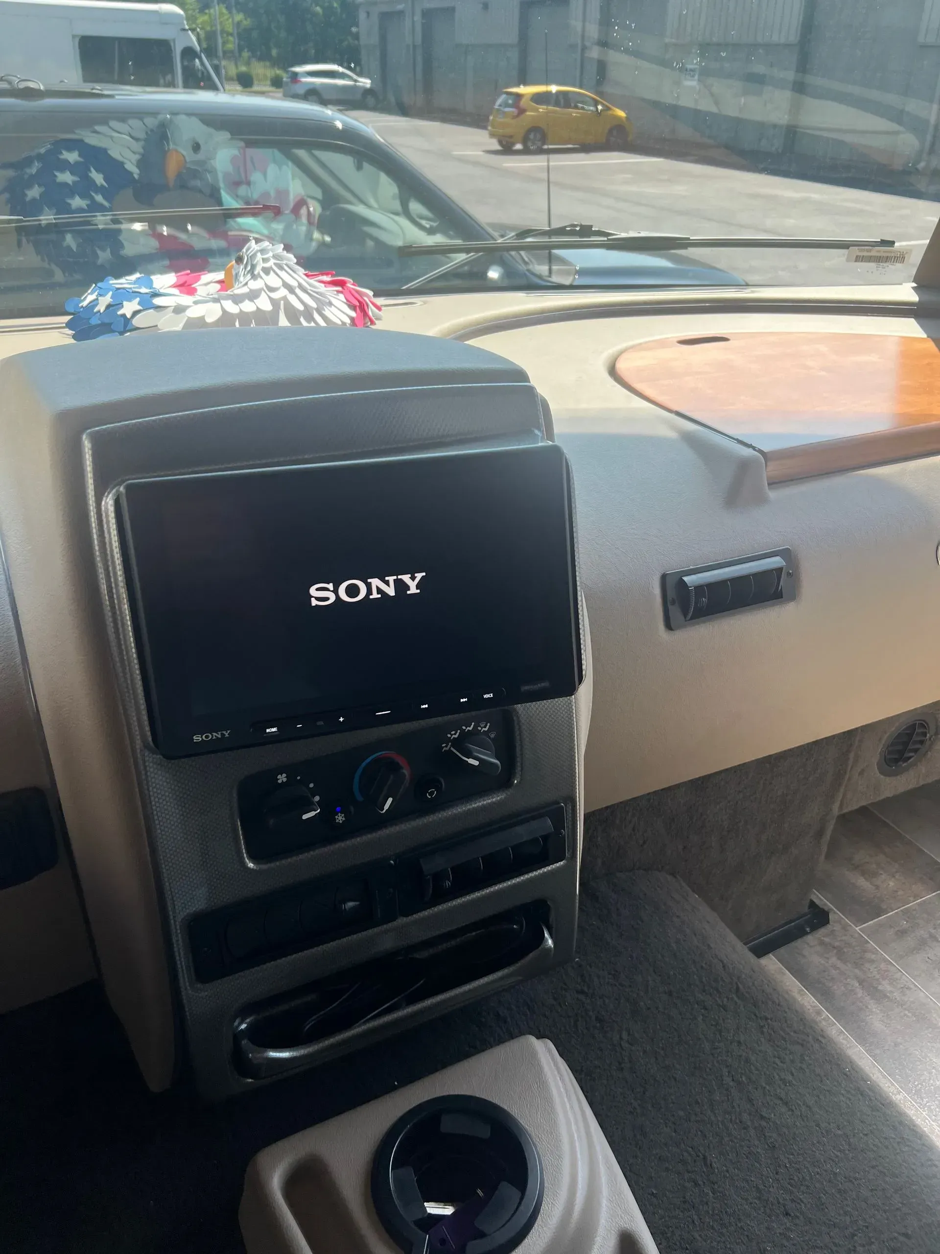 Interior dashboard of a vehicle with a Sony touchscreen display, cup holder, and tan-colored trim.
