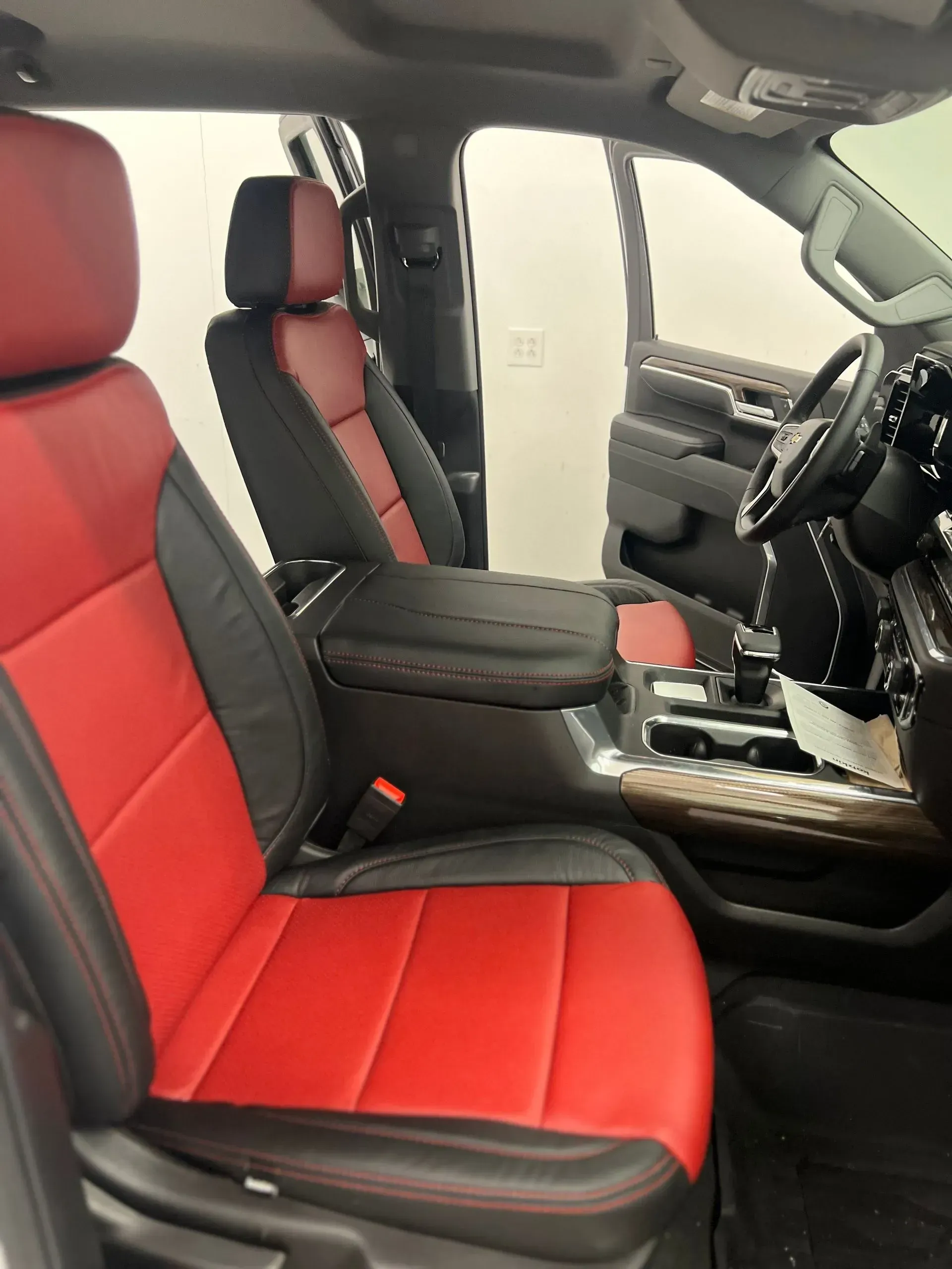 Red and black leather car interior with driver's seat and center console.