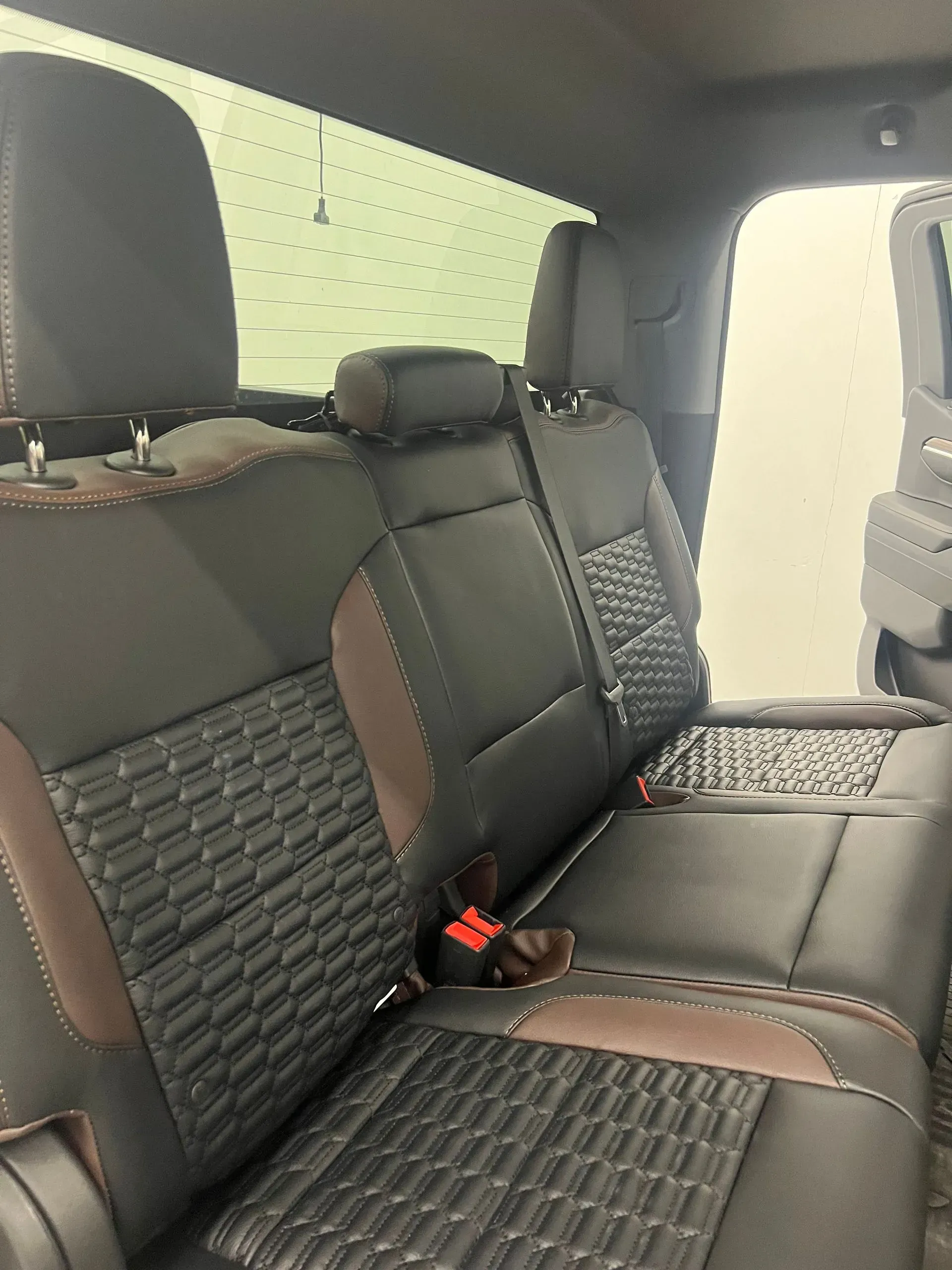Black and brown truck seats with textured patterns and headrests. A seat belt is visible.