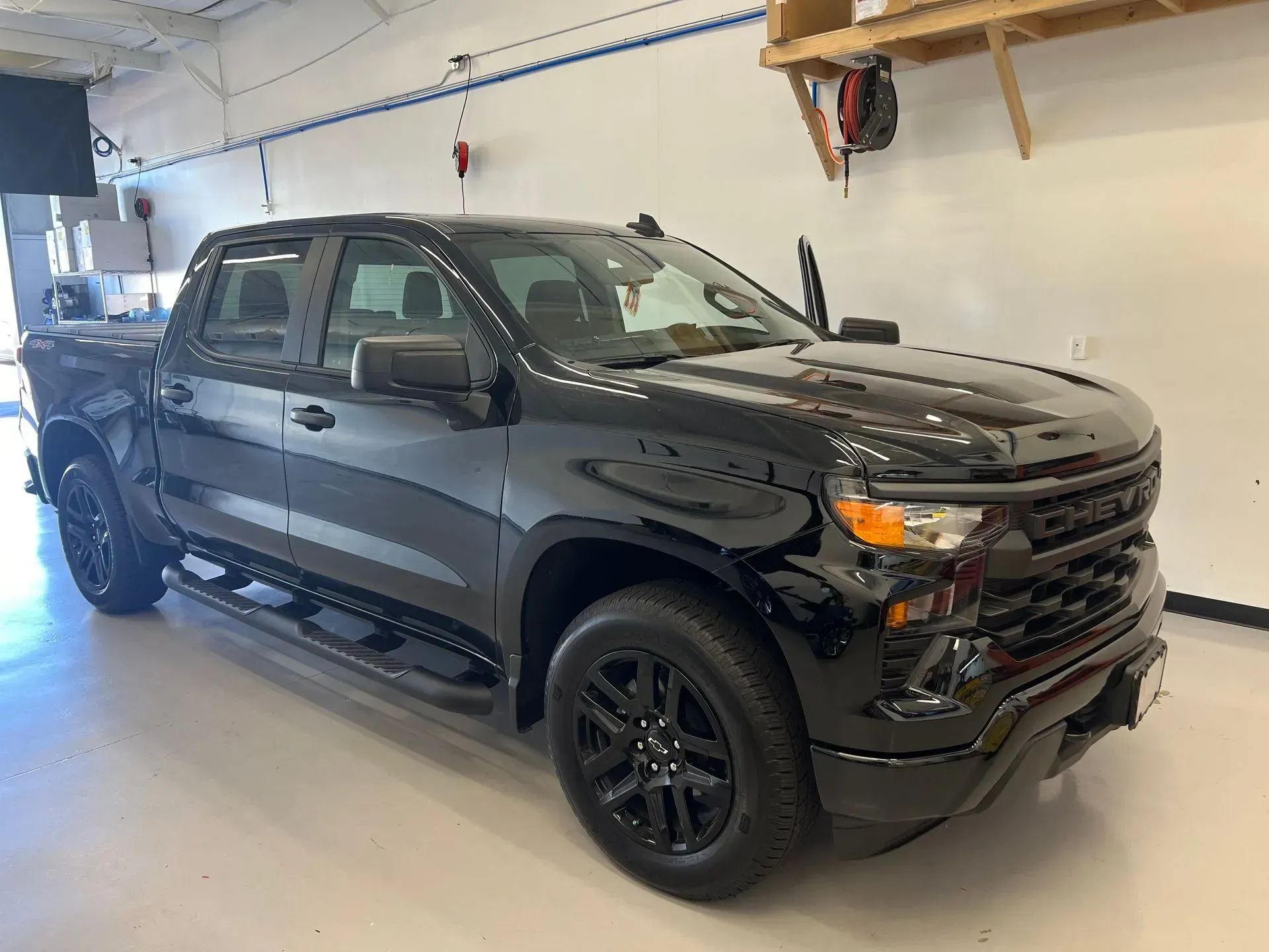 Black Chevrolet pickup truck parked indoors with black wheels.