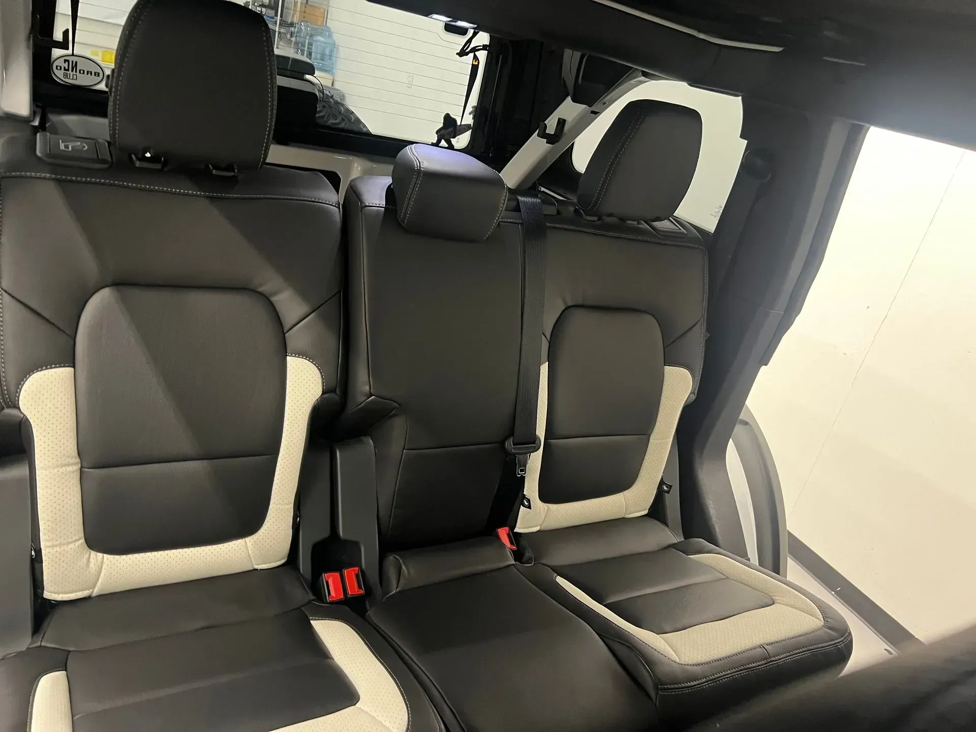 Interior rear seats of a vehicle. Black leather with white trim.
