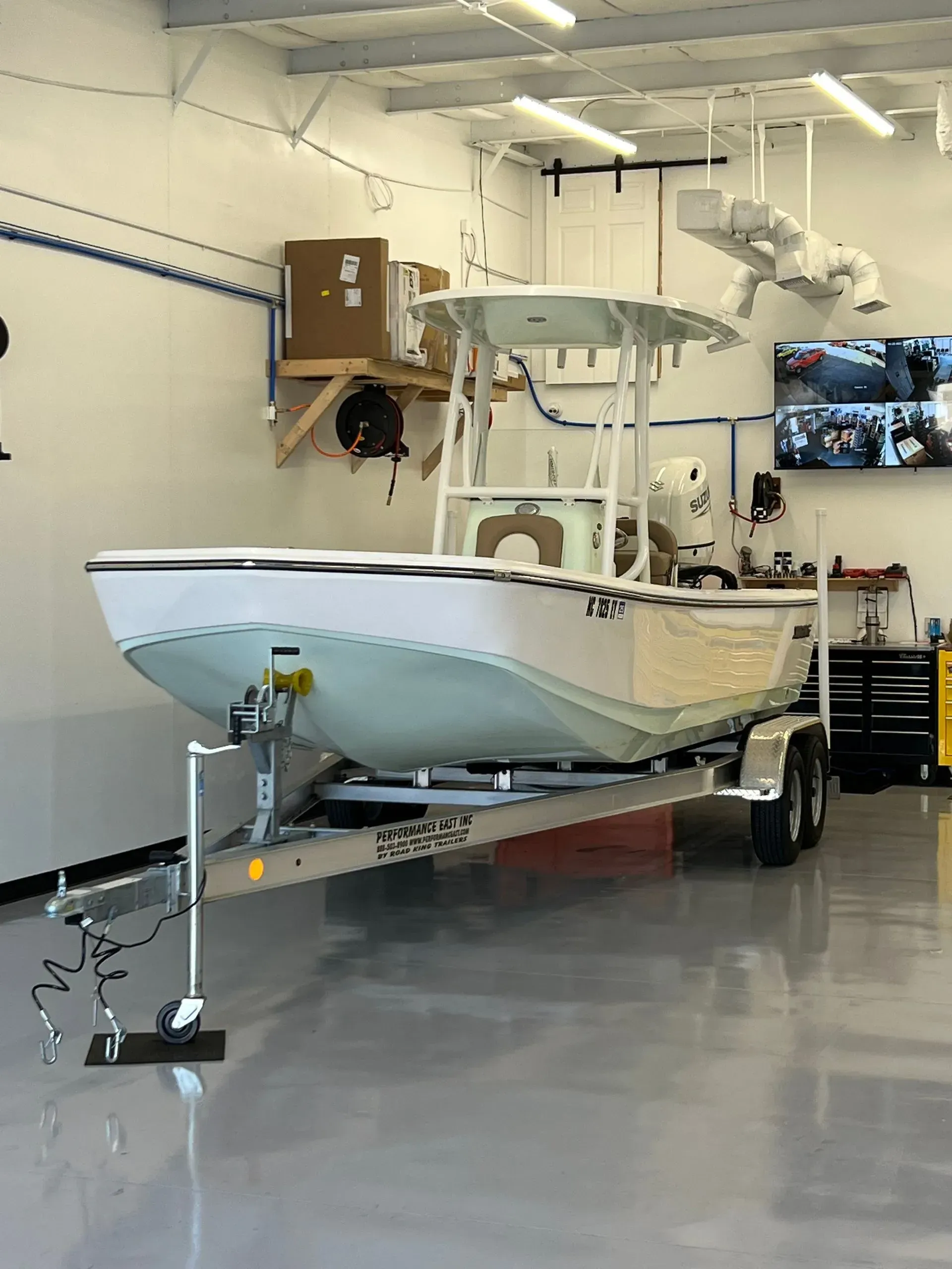 A white boat on a trailer inside a brightly lit garage.