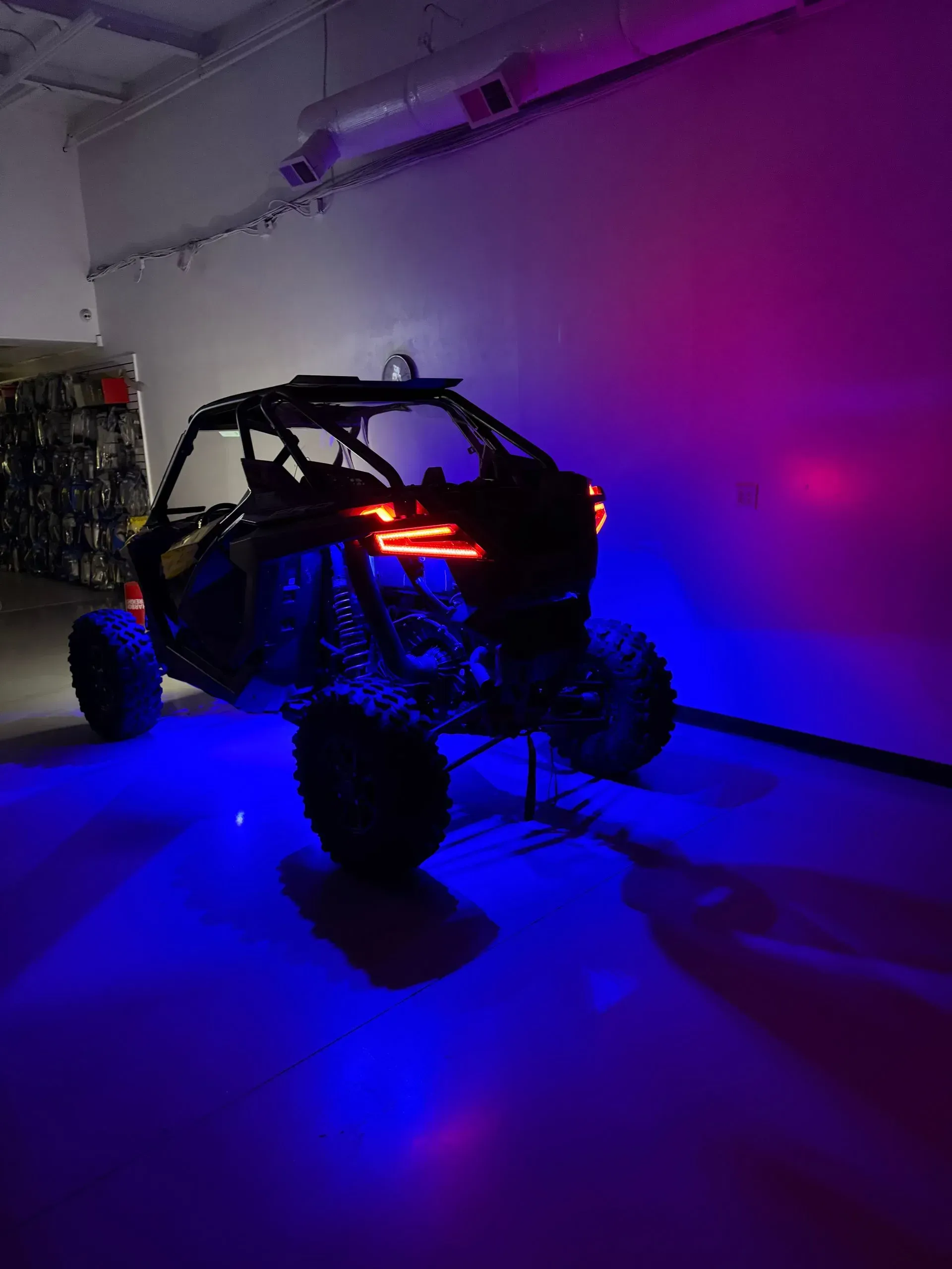 Off-road vehicle lit with blue and purple lights in a room.
