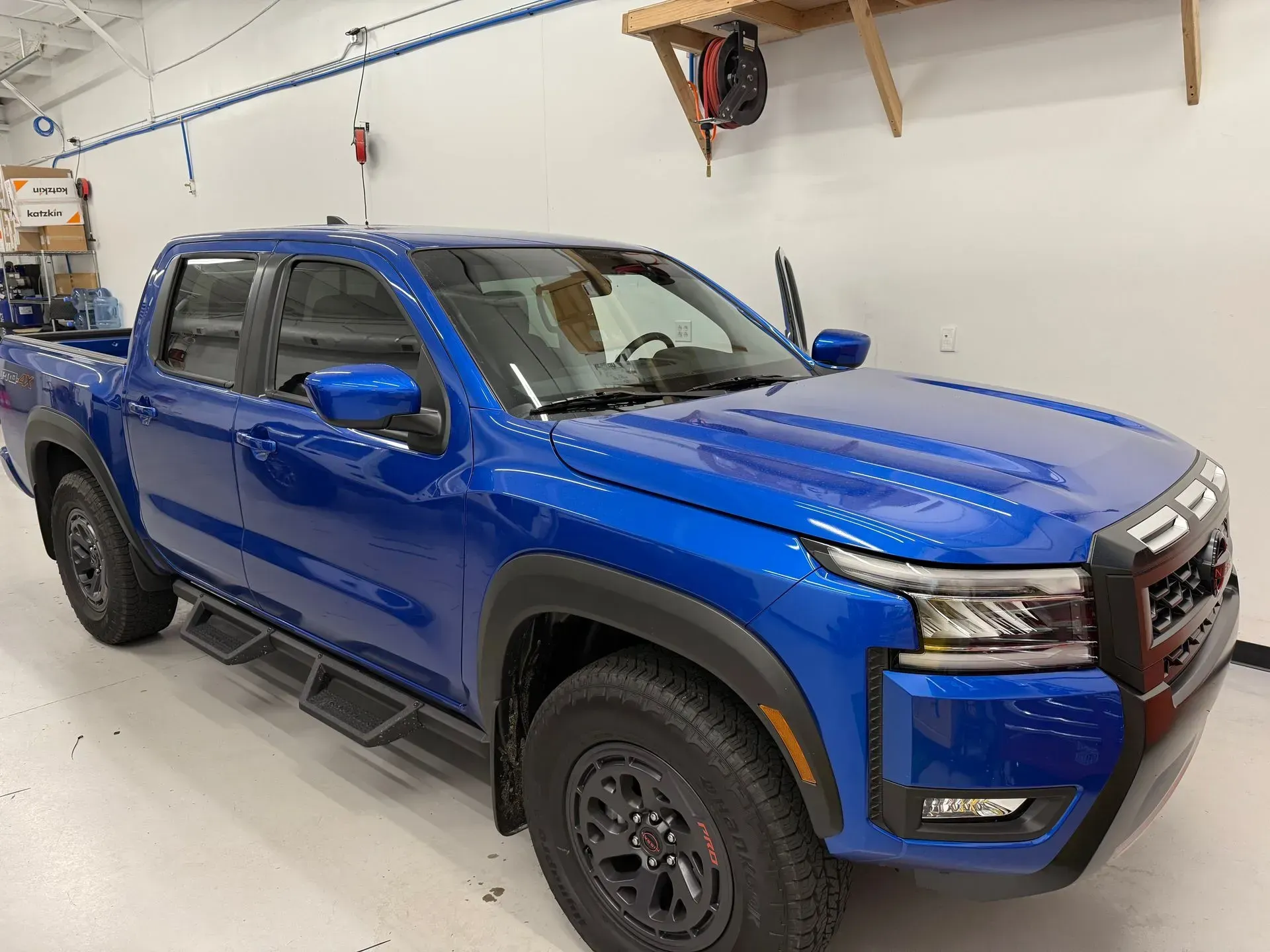Blue Nissan pickup truck in a shop, angled view.