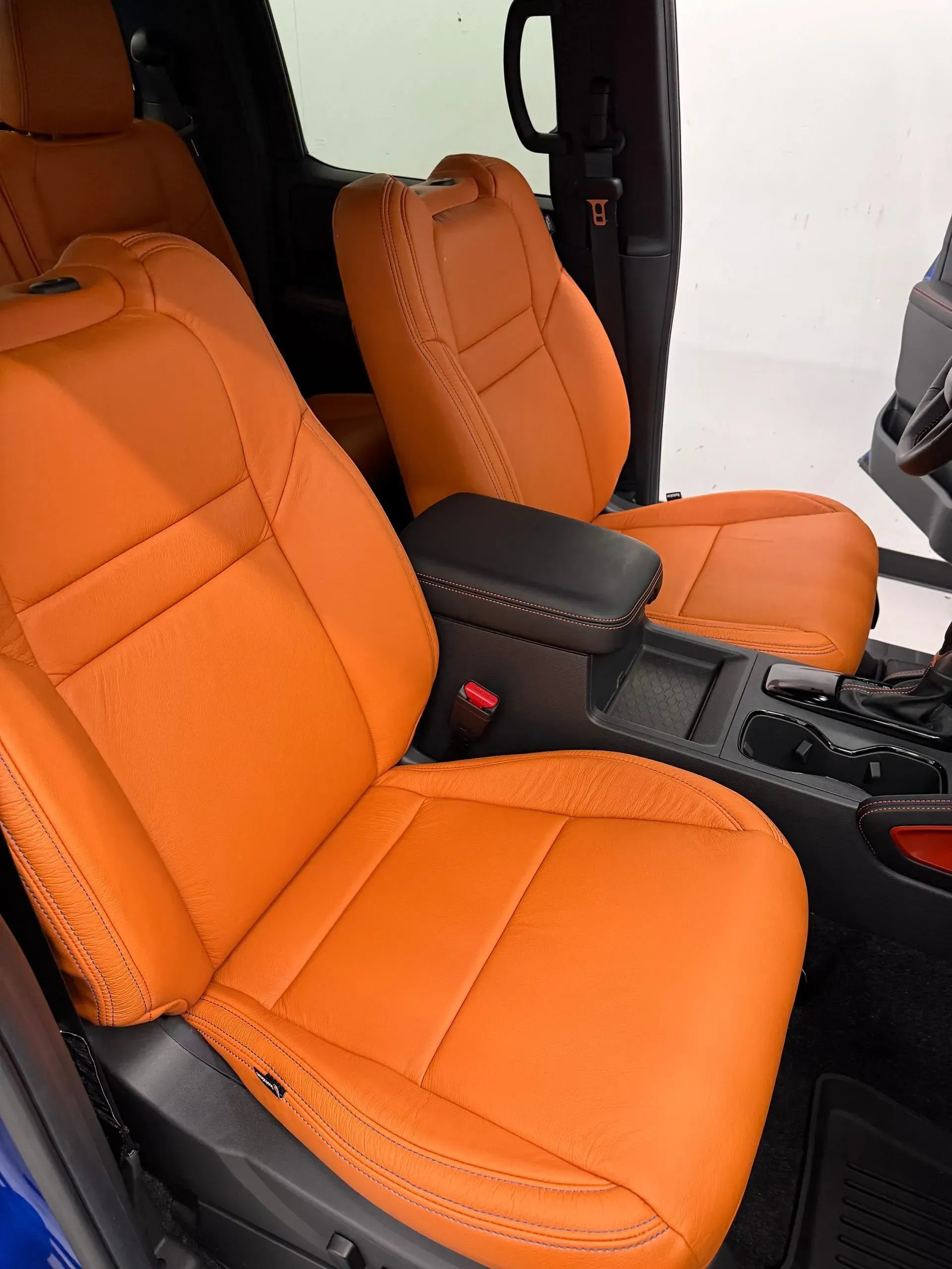 Bright orange leather car seats in a vehicle interior with black console and accents.
