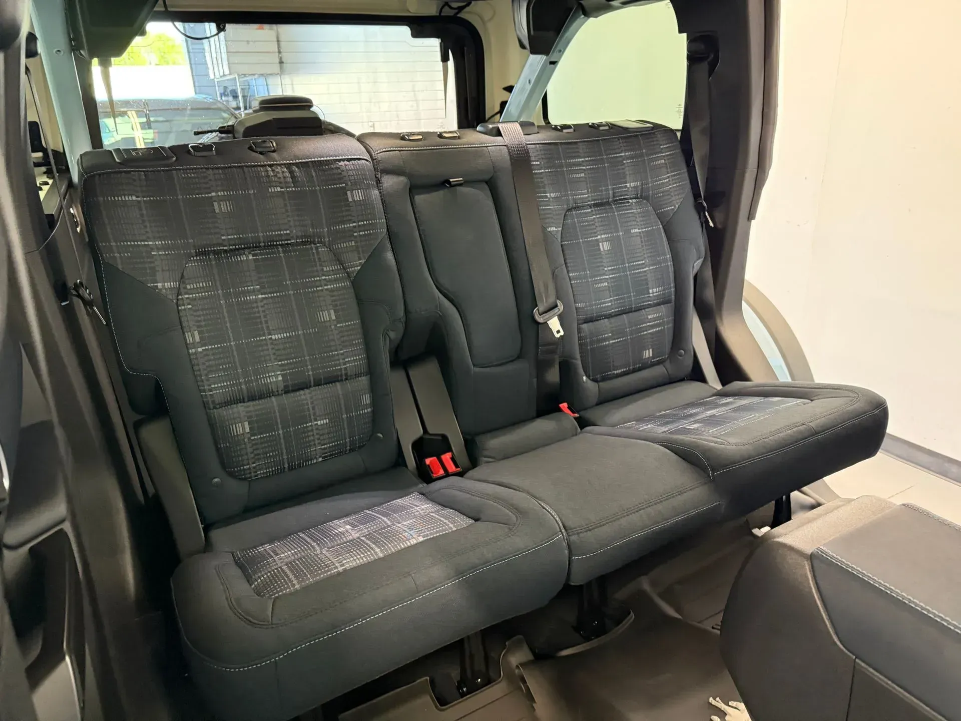 Rear seats of a dark-colored SUV, folded down, with seatbelts visible.