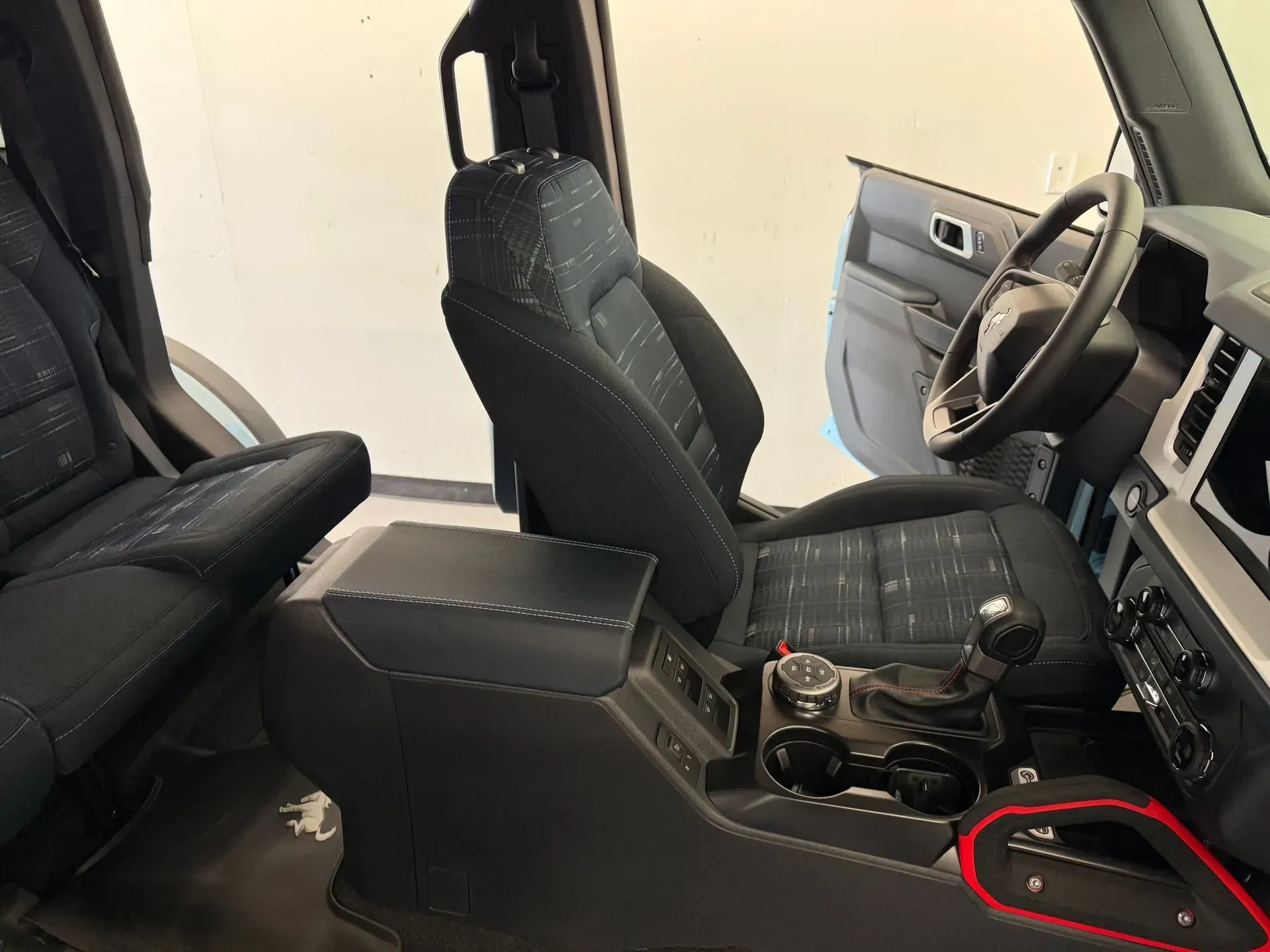Interior view of a black car. The focus is on the center console, seats, and dashboard. A door is open.