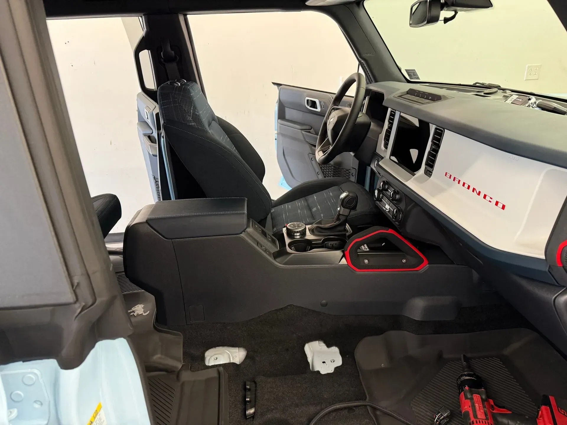 Interior view of a modern SUV dashboard, black and silver console, blue seat, and an open door.