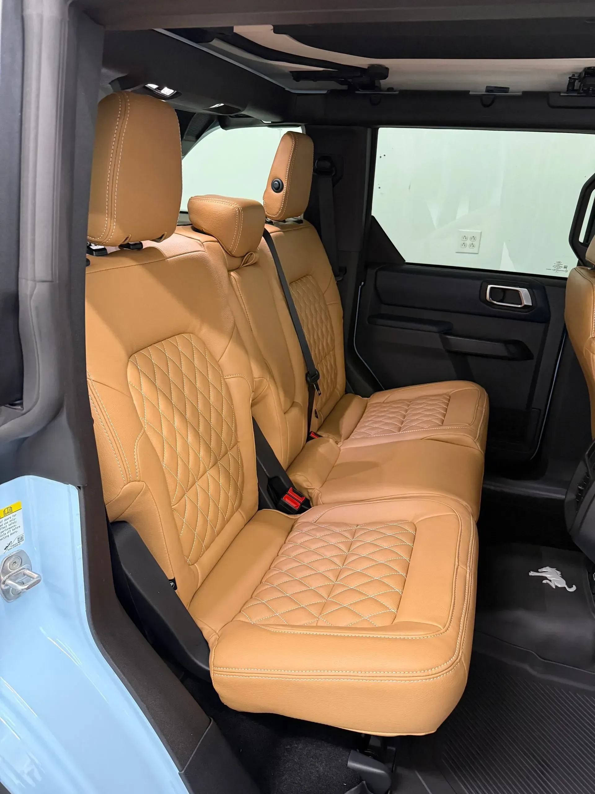 Tan quilted leather rear seats inside a blue and black vehicle.