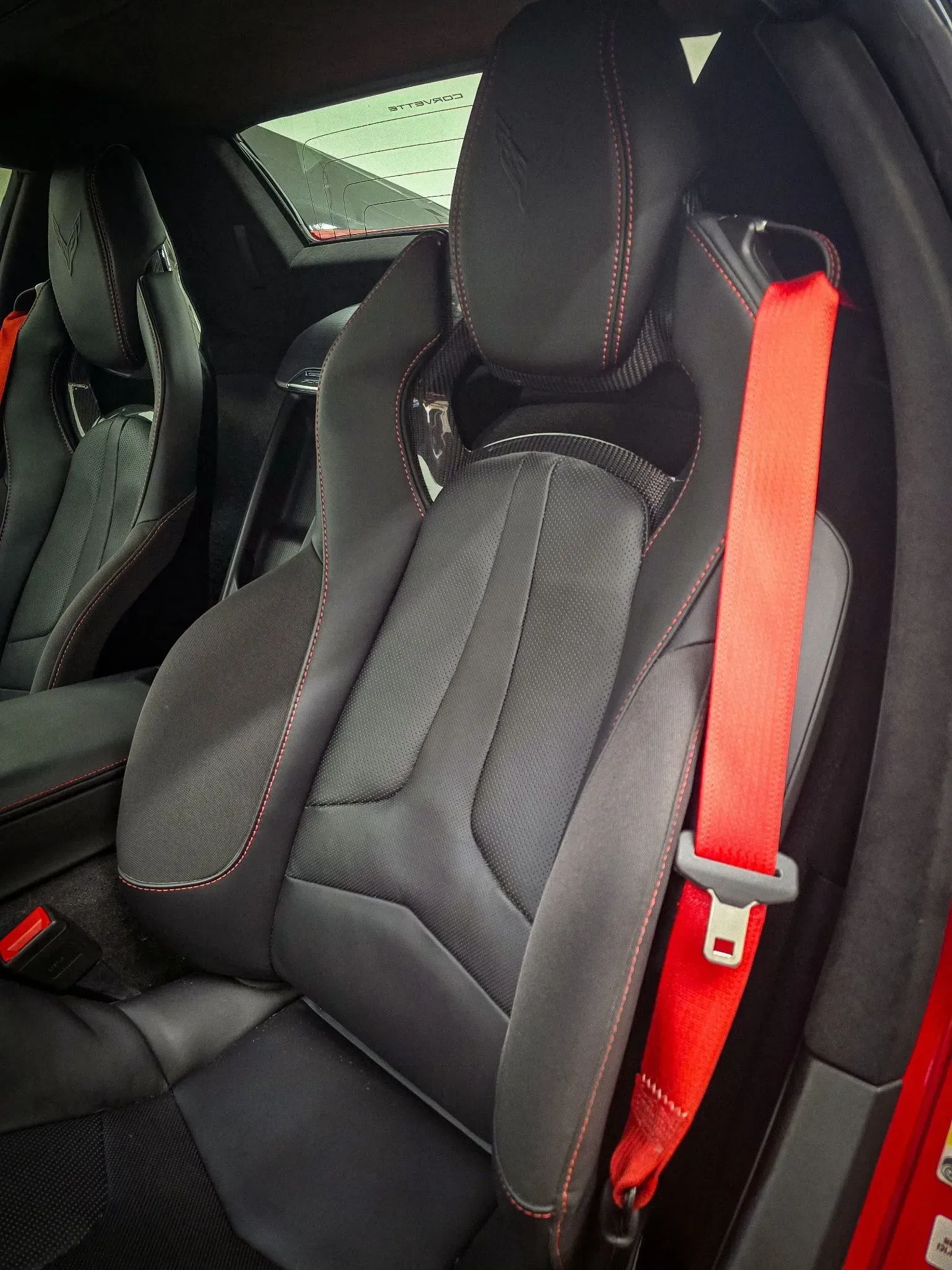 Black car seat with red stitching and seatbelt.