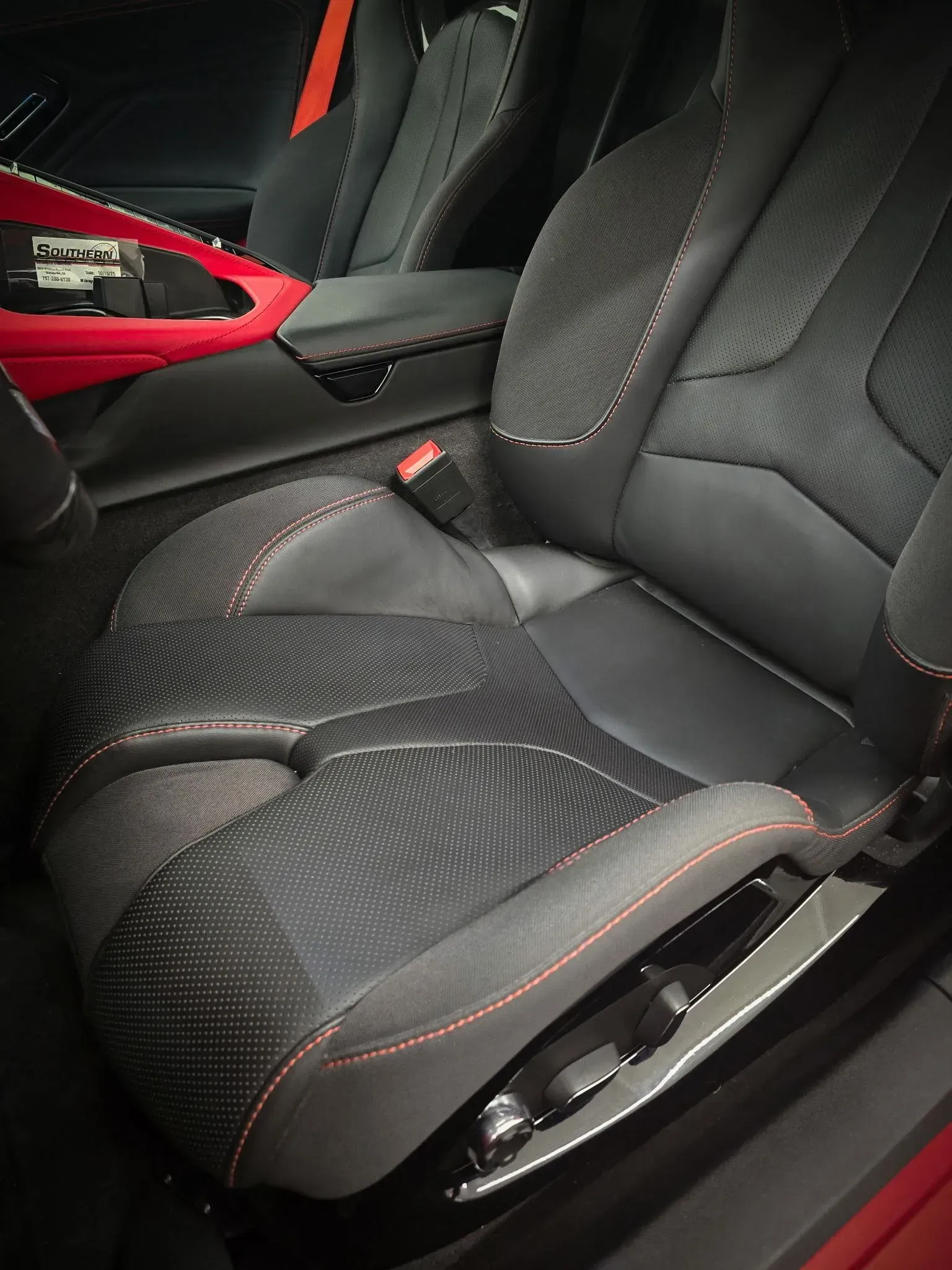 Black car seat with red stitching and accents.