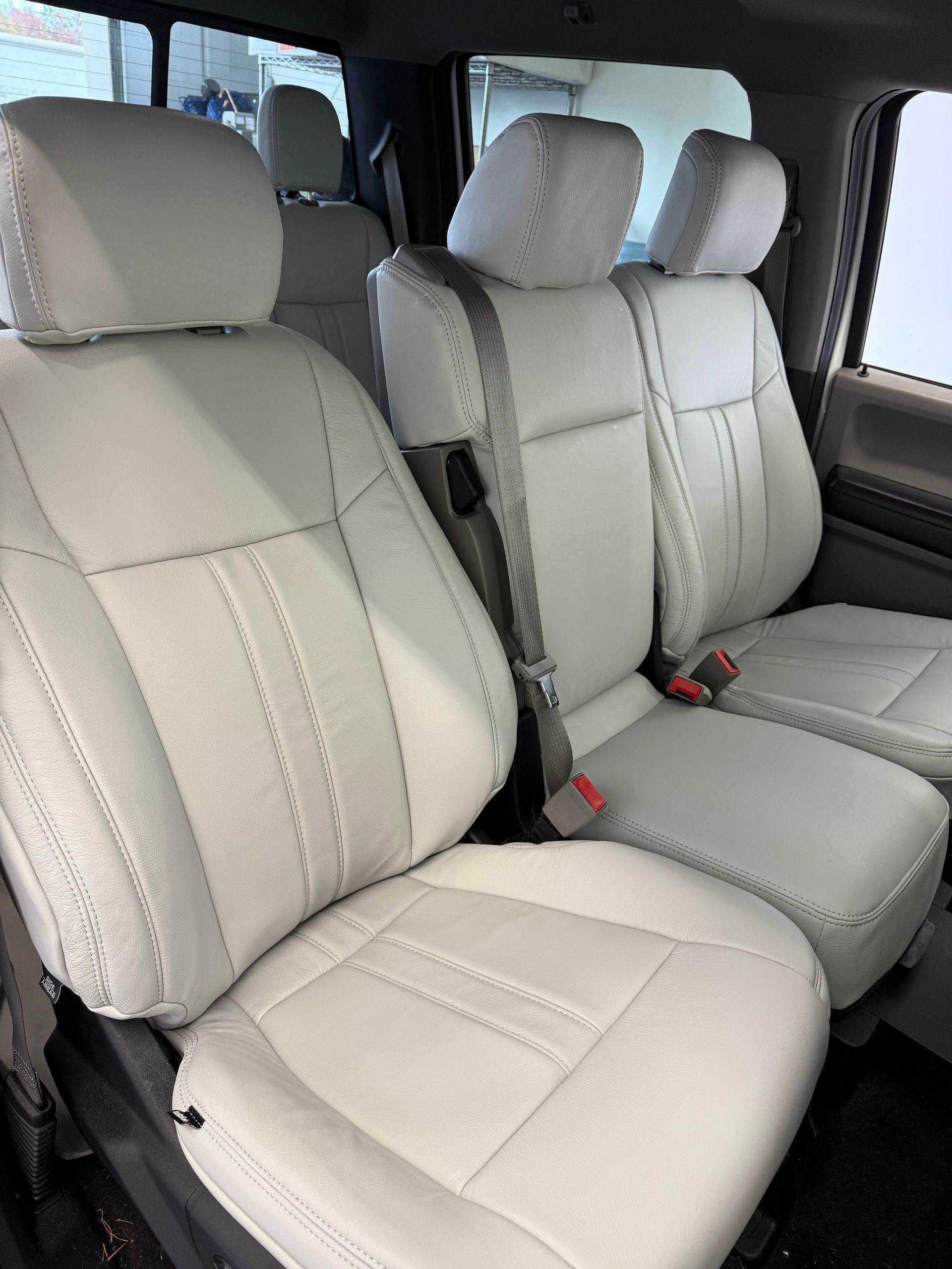 White leather car seats in the back of a vehicle.