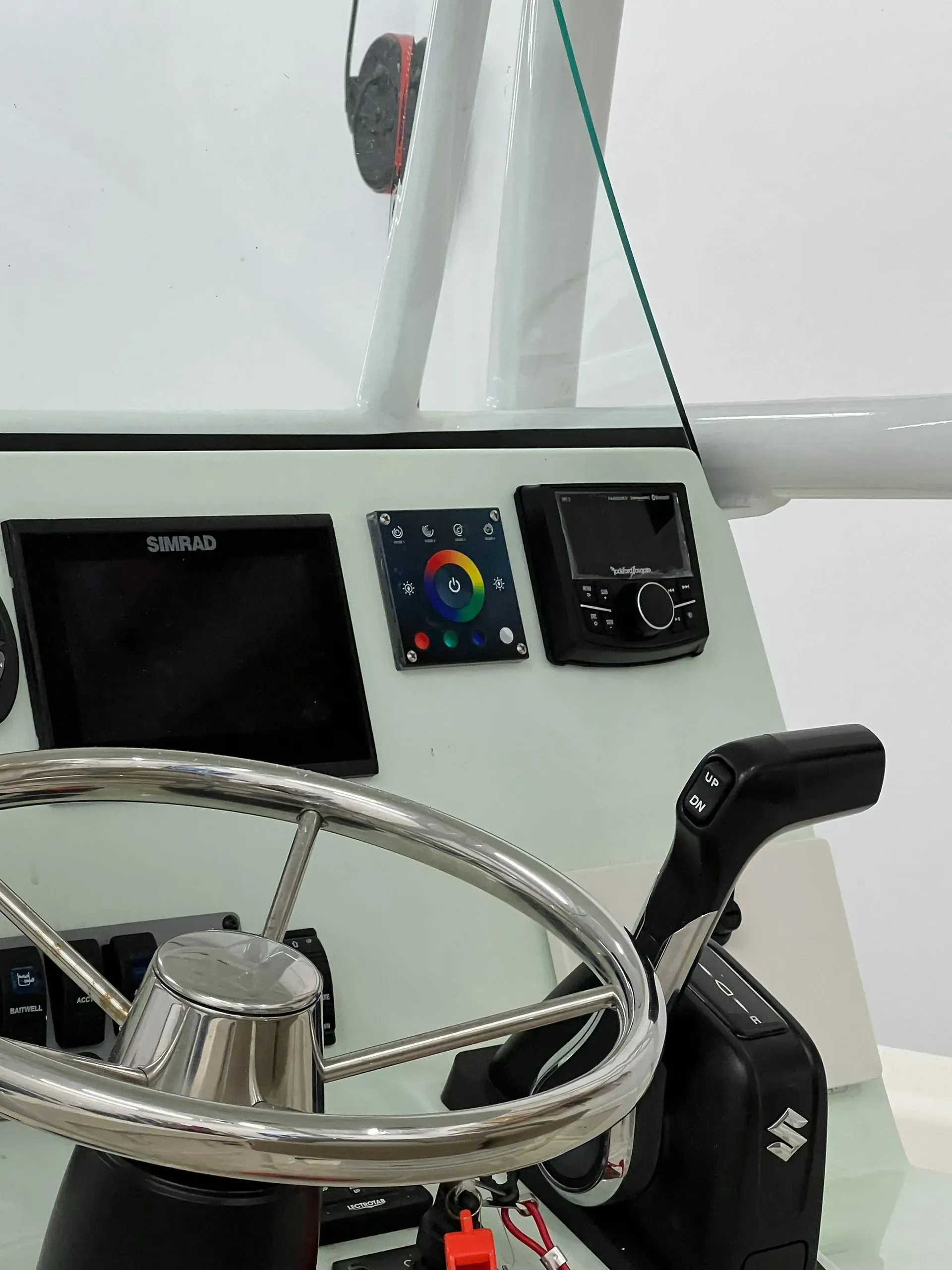 Boat dashboard with a steering wheel, gauges, and controls.