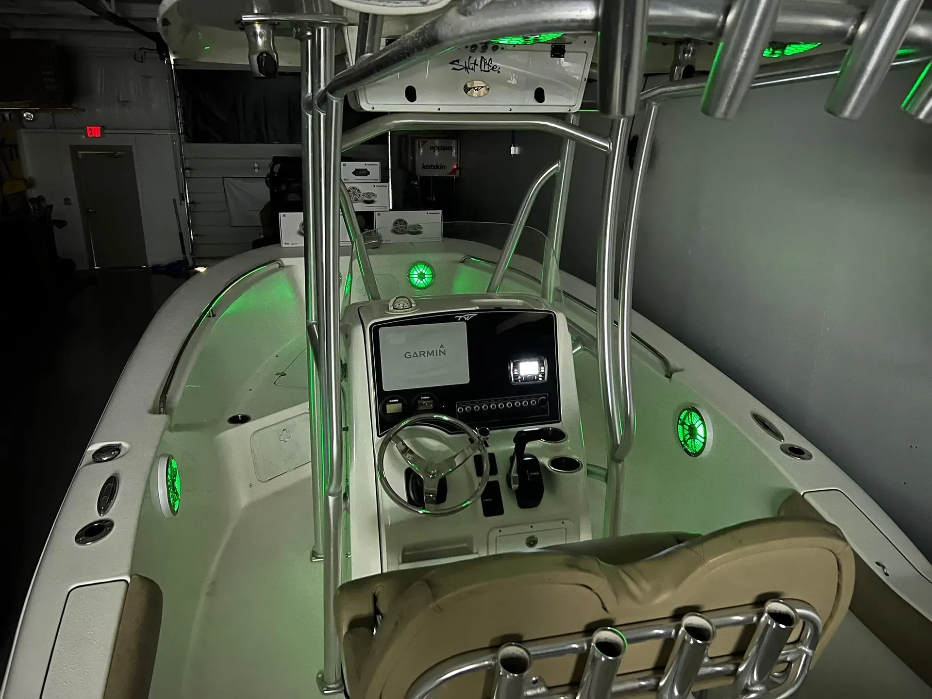 Boat interior with a center console, green lights, and a tan seat.