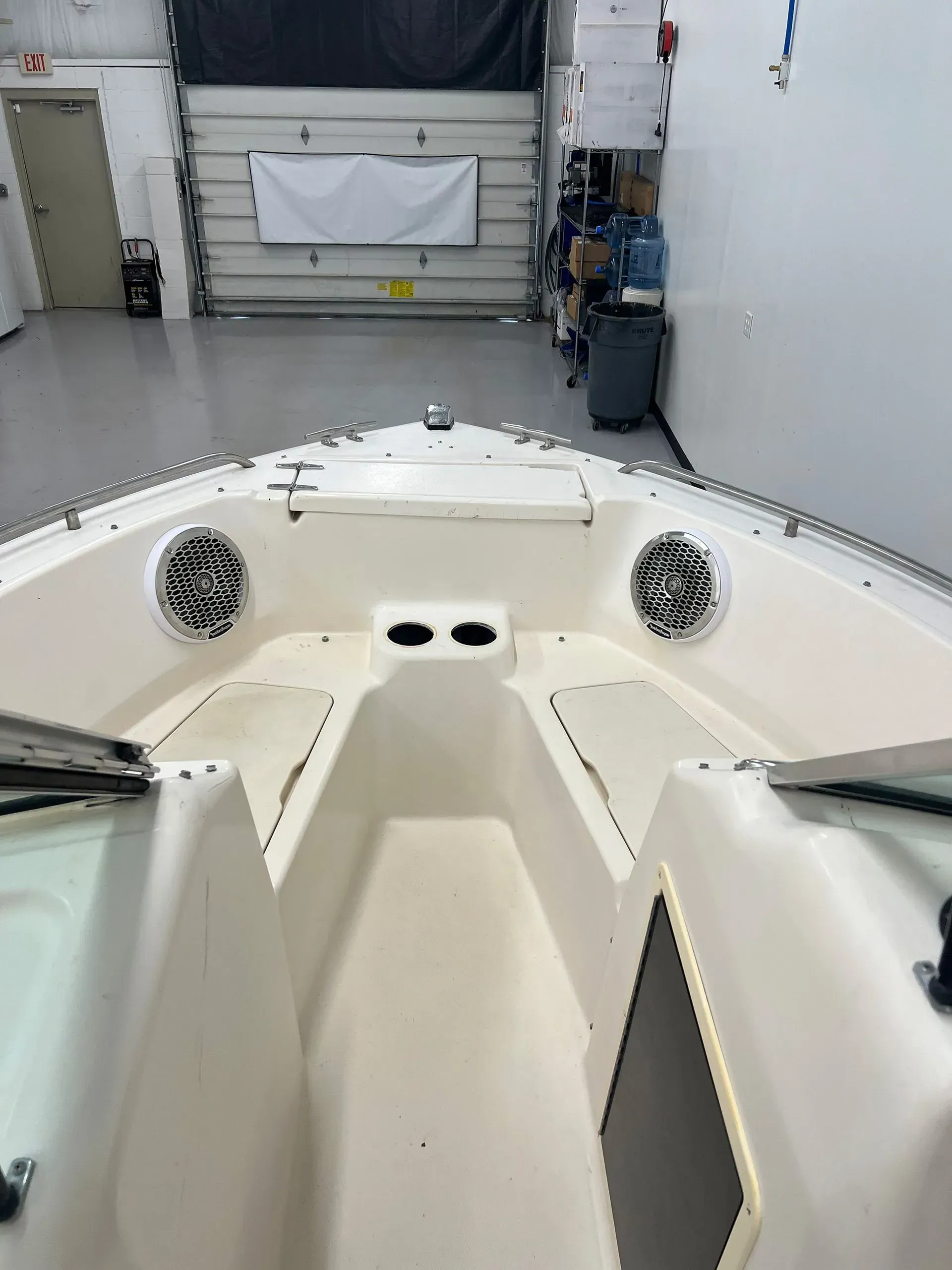 Boat interior with speakers, cup holders, and a view of a garage door in the background.