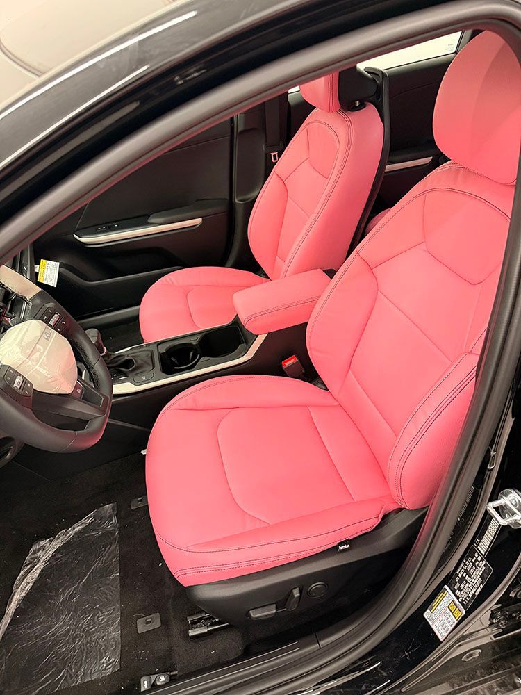 Black car interior with bright pink leather seats and armrest.