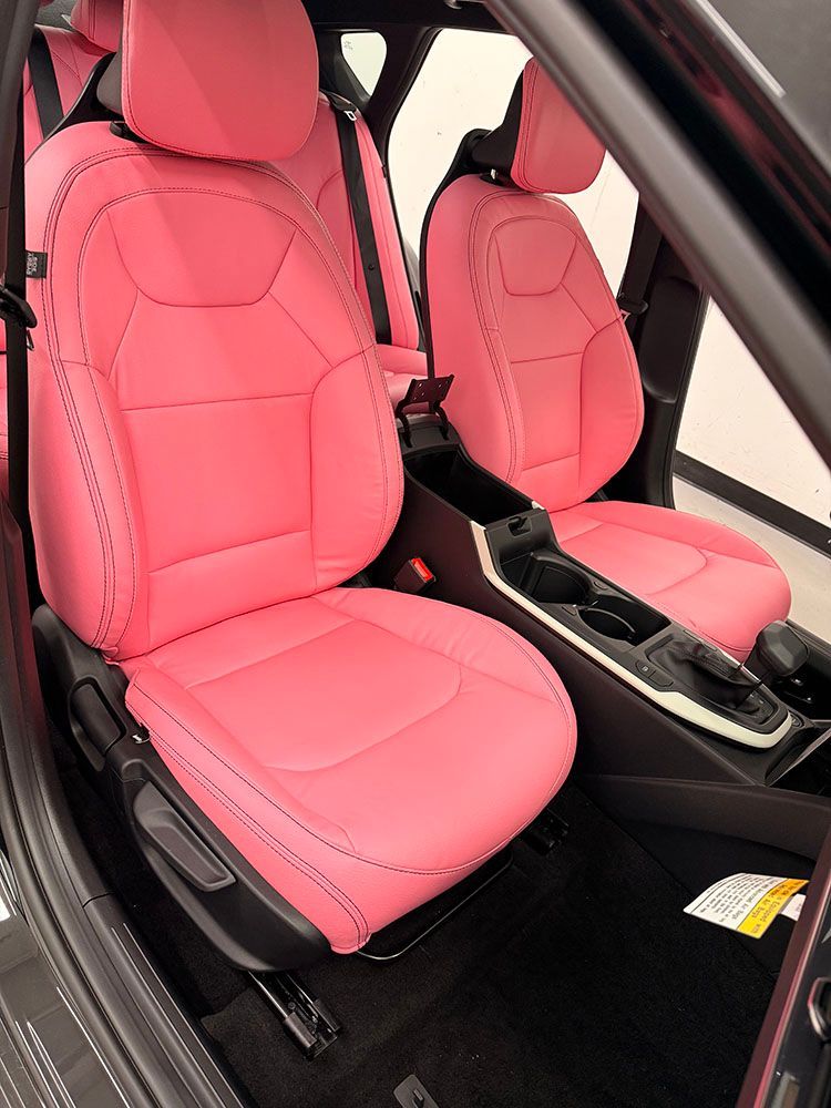 Pink car interior with seats, armrest, and black floor.