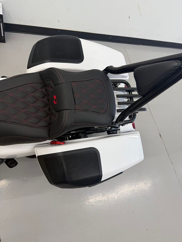 White motorcycle with black seat and cargo containers.