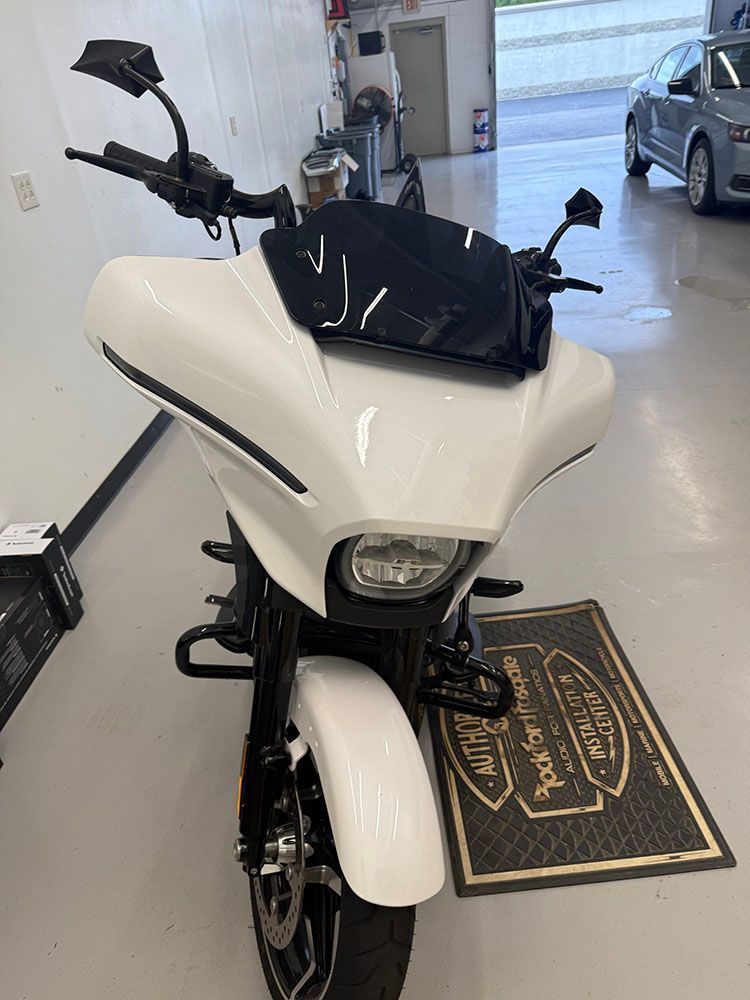 White motorcycle with black accents in a shop, front view.