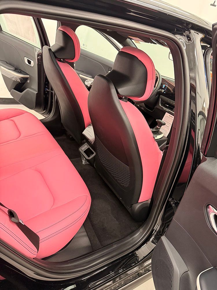 Interior car shot with pink and black seats. Rear door open, showing seats and floor.