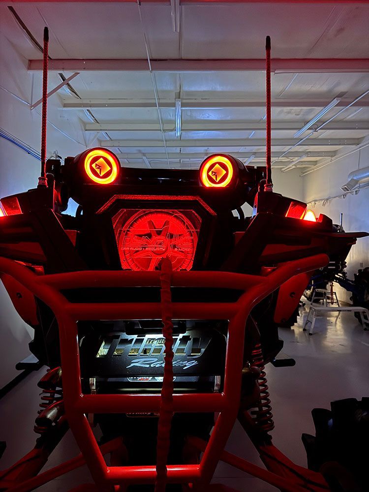 Red off-road vehicle with glowing lights, in a workshop.