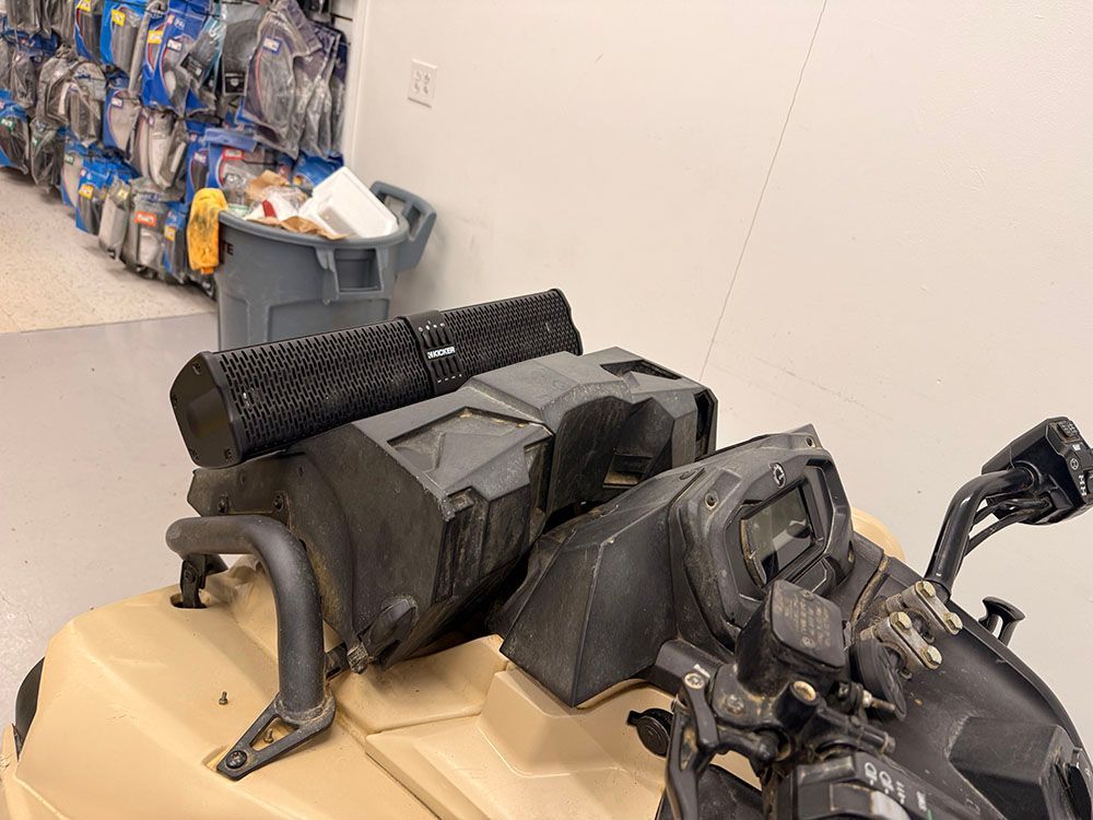 Black speaker system and storage compartment mounted on an ATV, indoors.