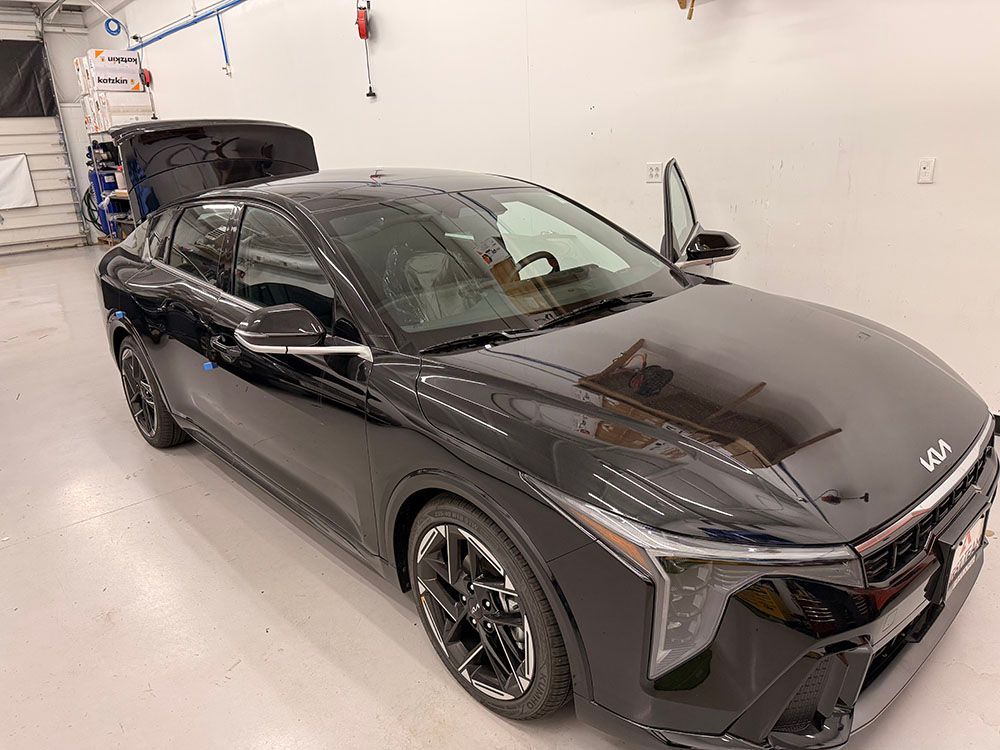Black Kia EV6 parked inside a brightly lit garage, door and trunk open.