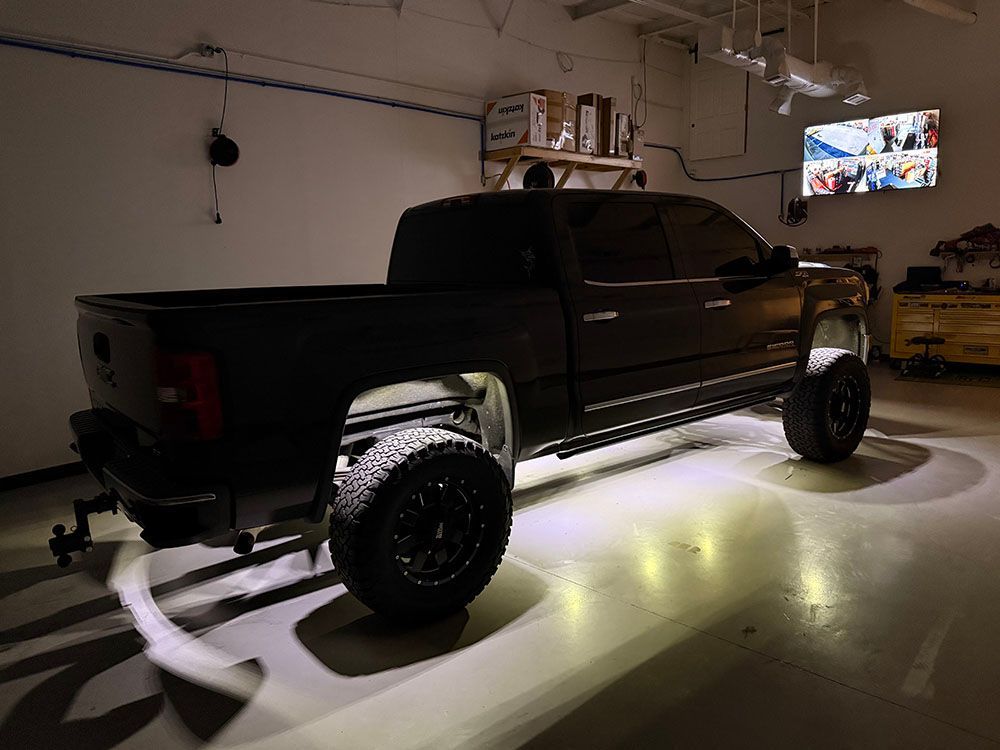 Black pickup truck with underglow lighting in a garage.