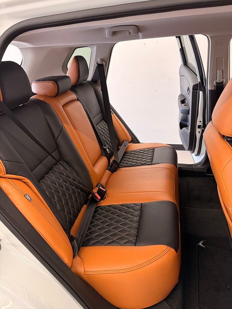 Rear car seats: black and orange leather upholstery. Seat belts visible. Interior of a white vehicle.