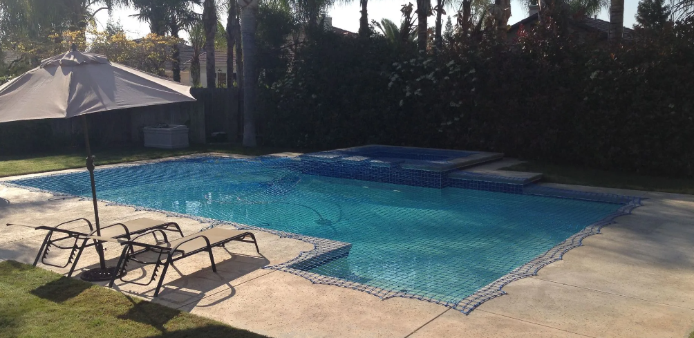 Backyard swimming pool with lounge chairs and a shaded patio umbrella