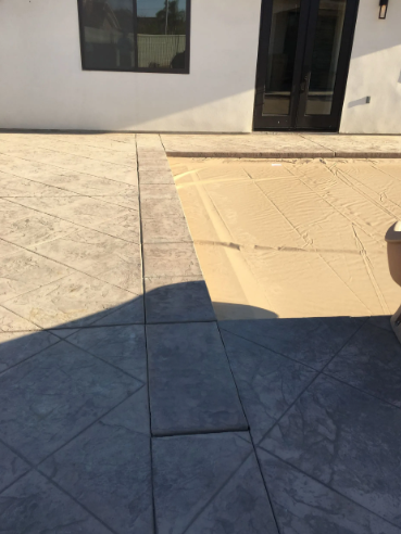 Sunlit stone patio beside a beige building, with geometric shadow across the ground