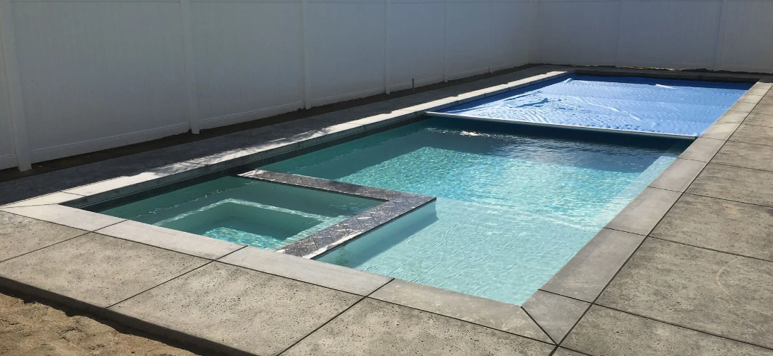 Rooftop swimming pool with clear blue water, surrounded by light stone decking.